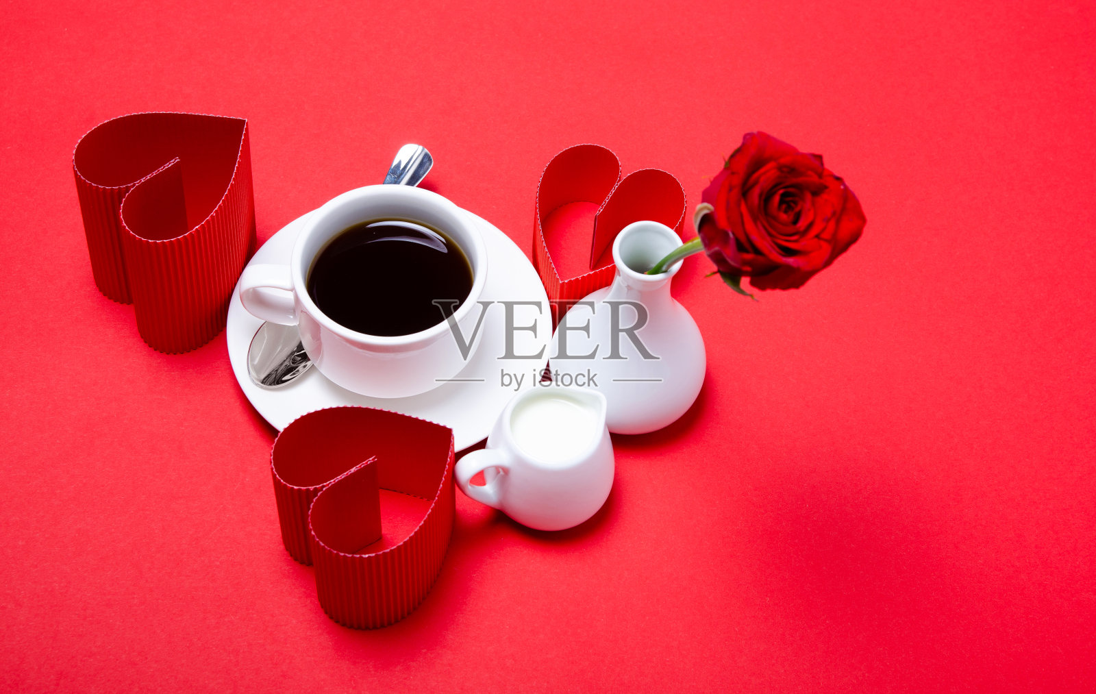 白花瓶上插着一朵红玫瑰，还有一杯牛奶咖啡，硬纸板做的心照片摄影图片
