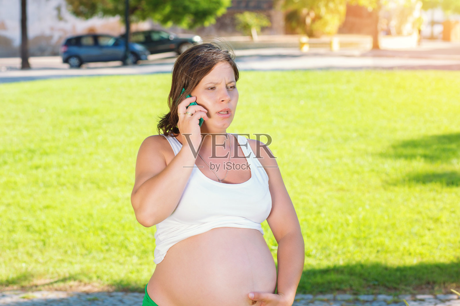 情绪激动的孕妇在户外用手机说话照片摄影图片
