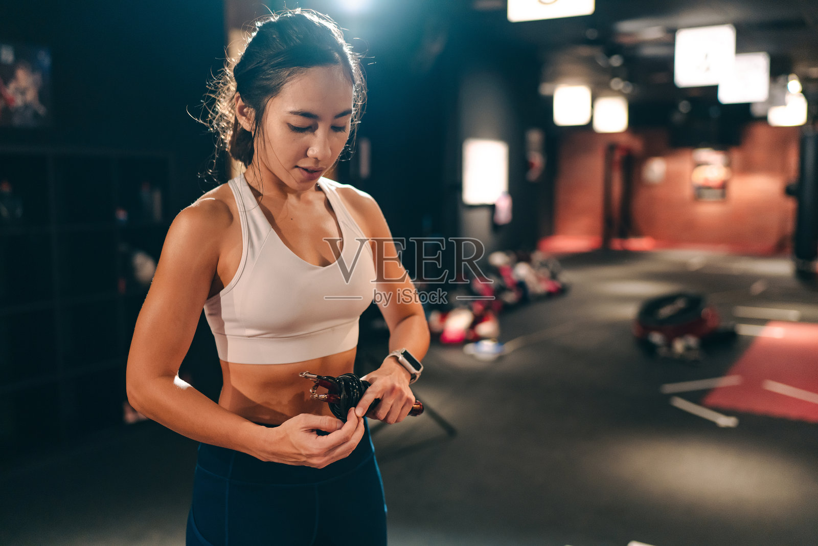 美丽的亚洲女性保持一个跳绳在健身房照片摄影图片