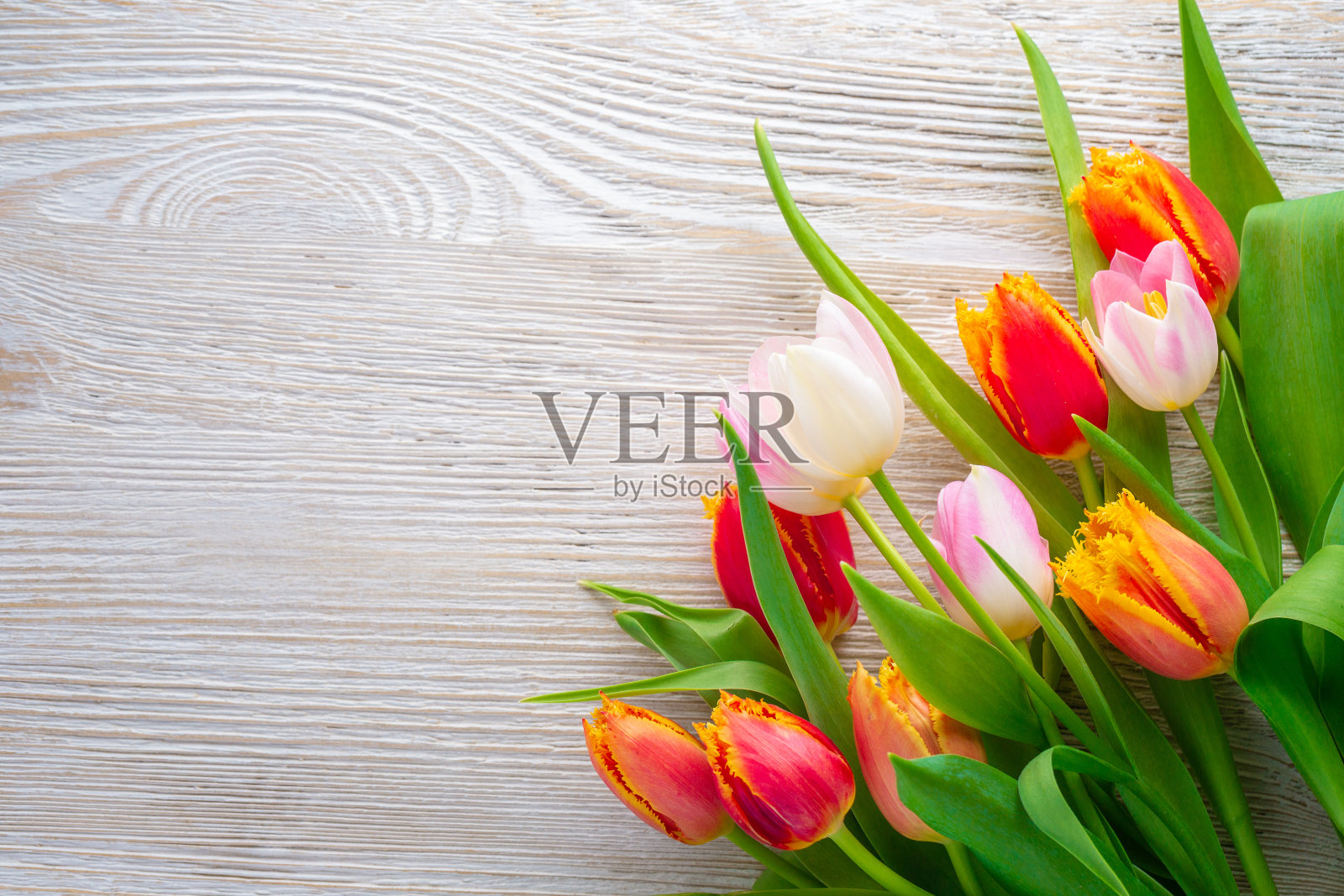 木桌上放着一束郁金香。春假概念背景。照片摄影图片