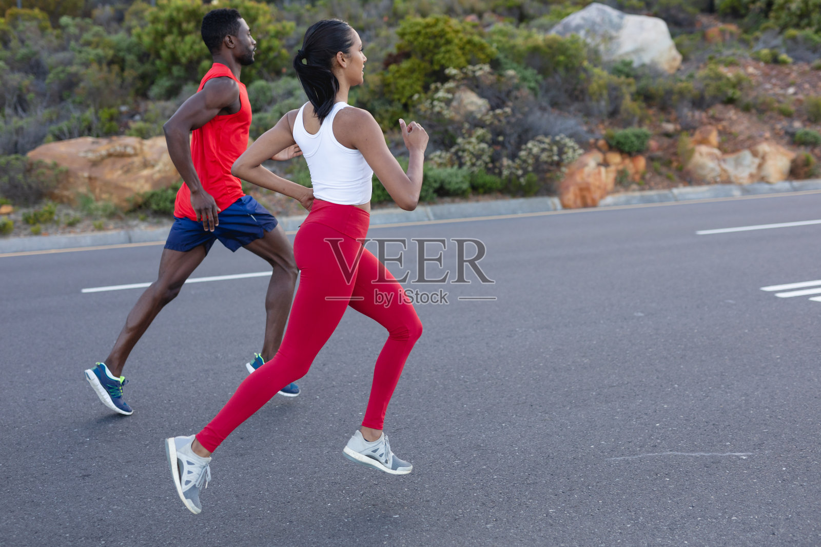 穿着运动服的非裔美国夫妇在沿海公路上跑步照片摄影图片
