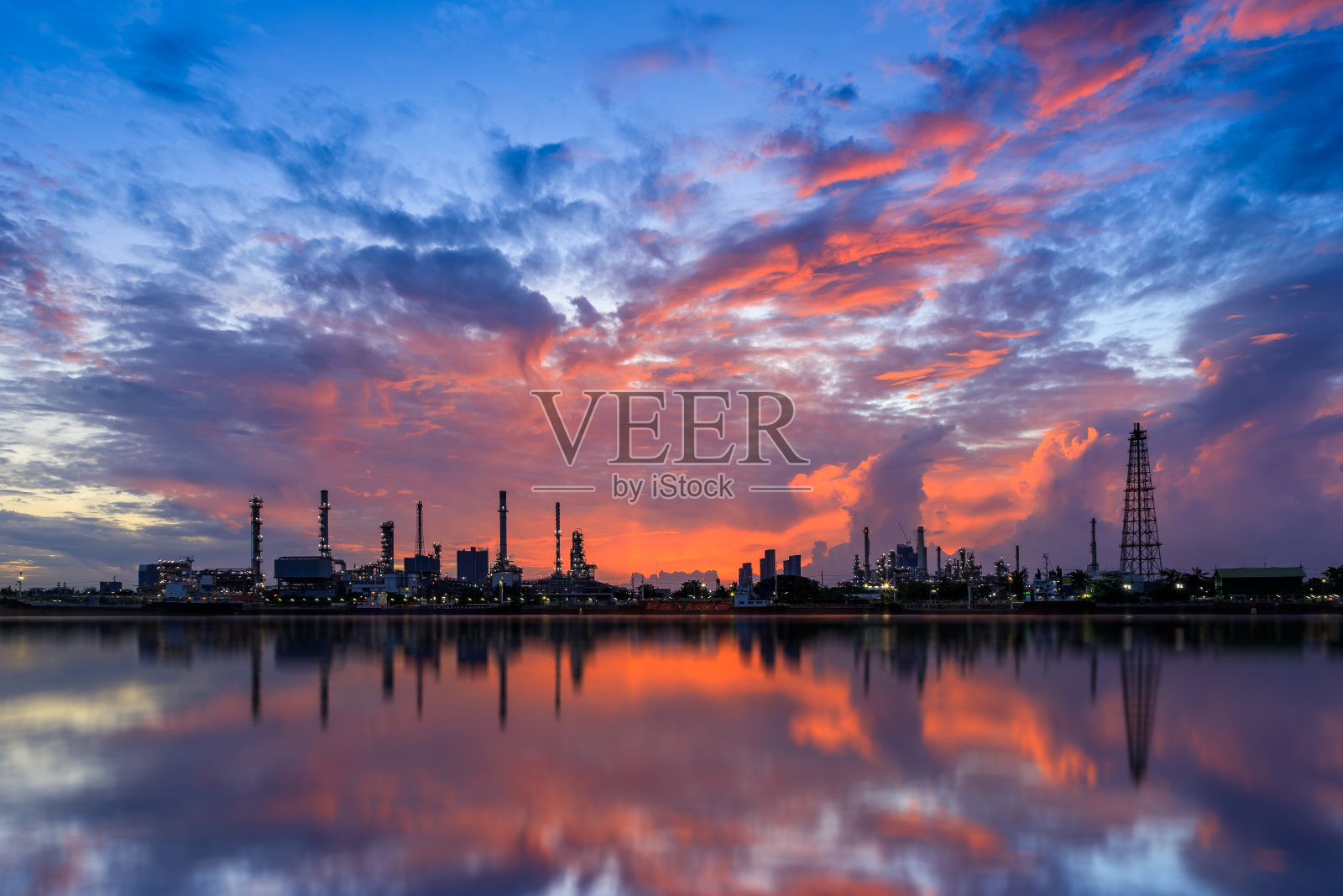 石油和天然气精炼厂工厂与反光河在黄昏。石化和能源行业概念。照片摄影图片