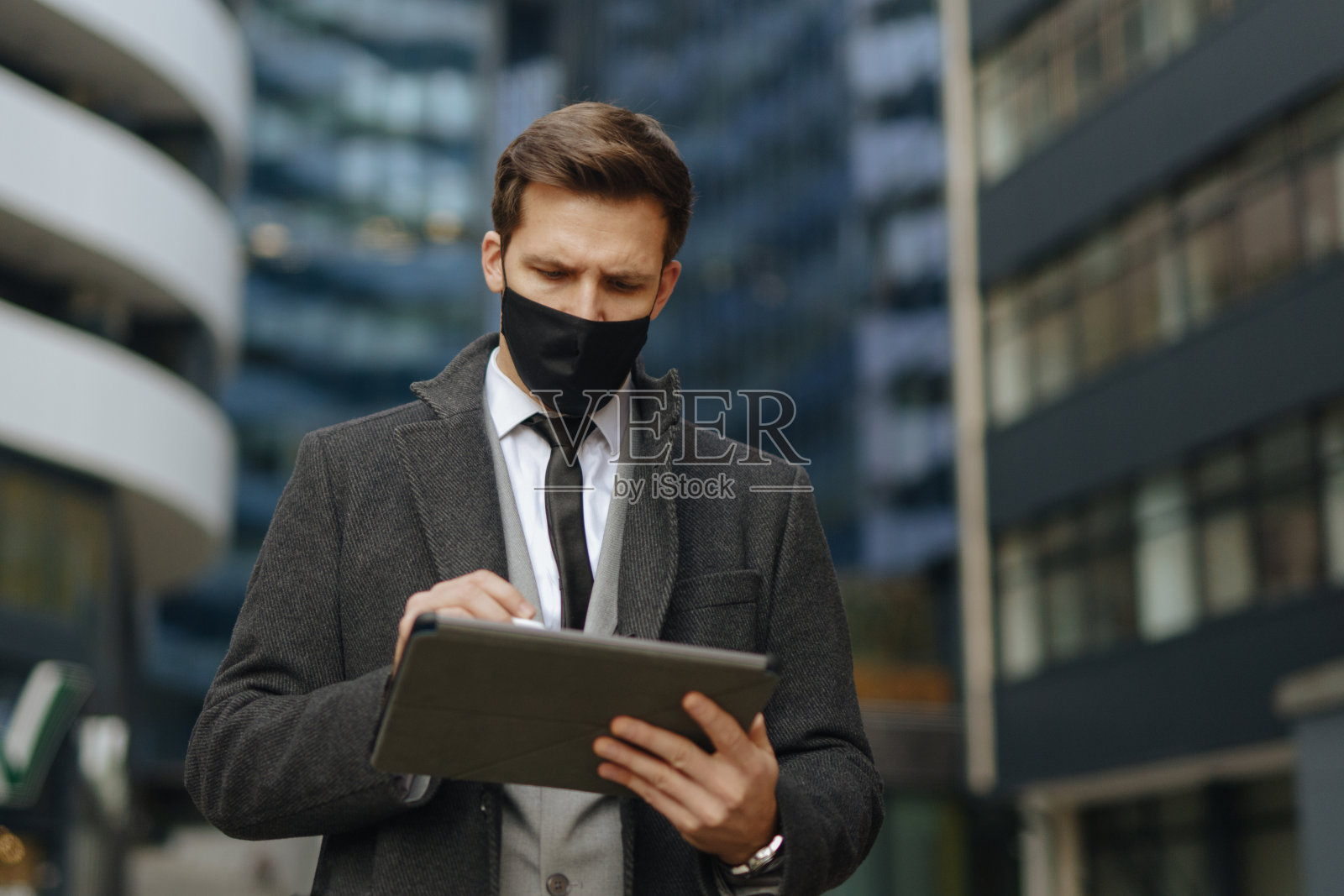 商人带着防护口罩在户外使用数码平板电脑照片摄影图片