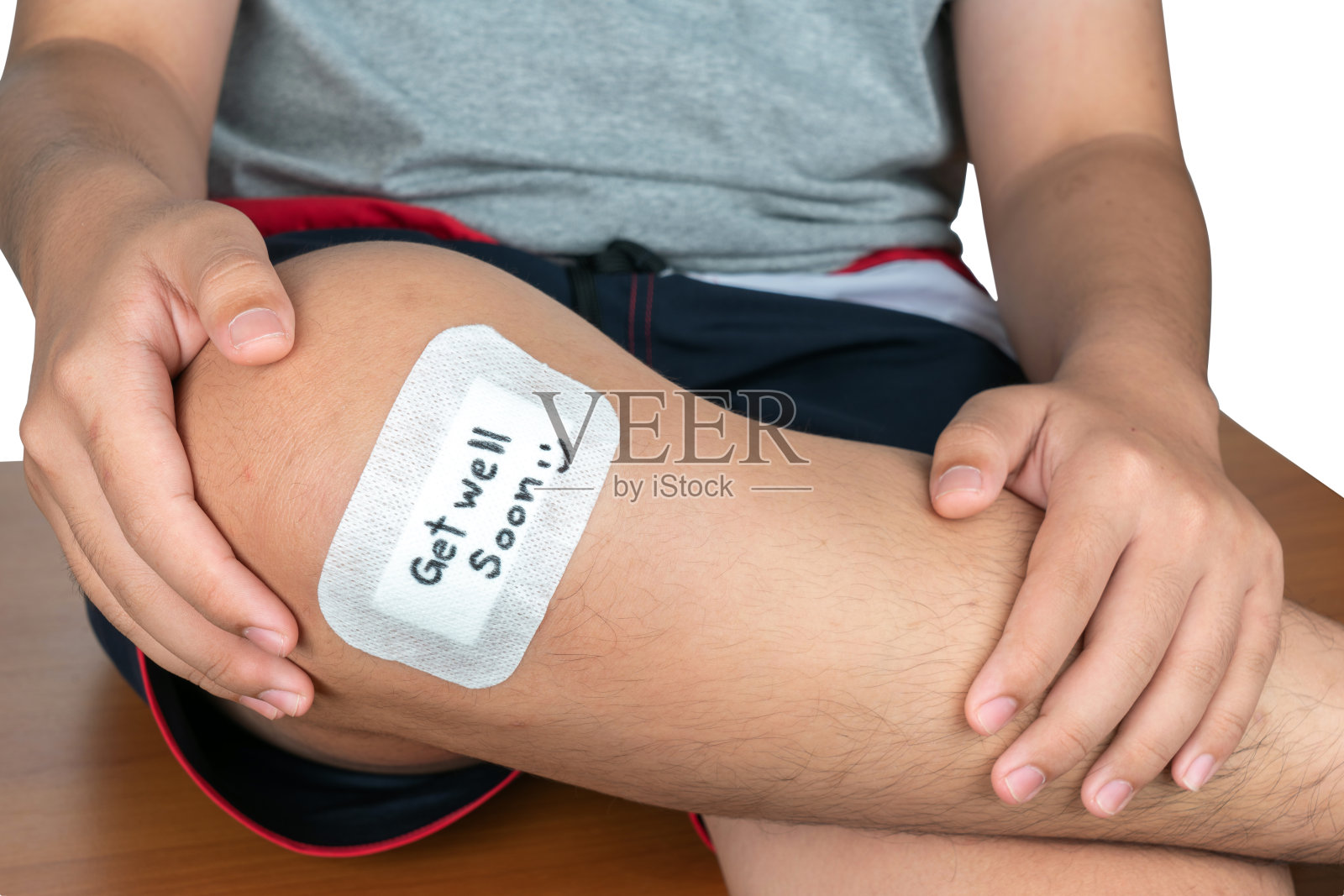 男孩的膝盖上贴着绷带或瘀伤，上面写着“早日康复”。一个亚洲男孩在他的膝盖上贴绷带。照片摄影图片