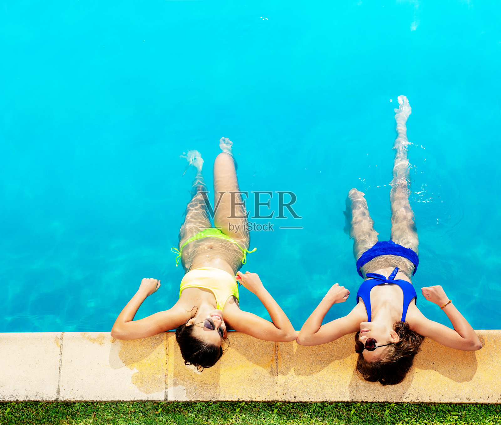 两个穿着比基尼的女孩在游泳池边上照片摄影图片