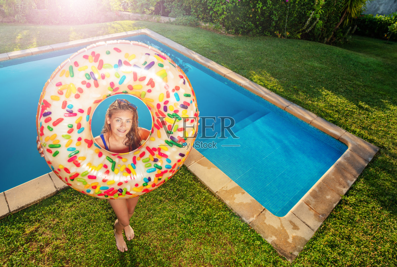 女孩和充气甜甜圈站在游泳池附近照片摄影图片
