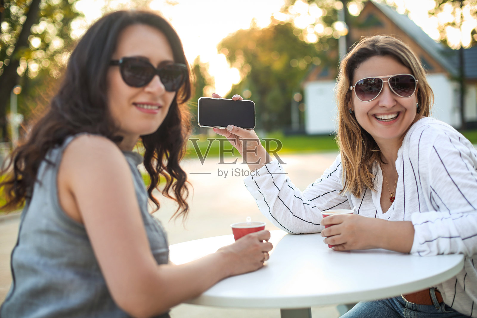 快乐的成年女性在街上拿着咖啡和手机照片摄影图片