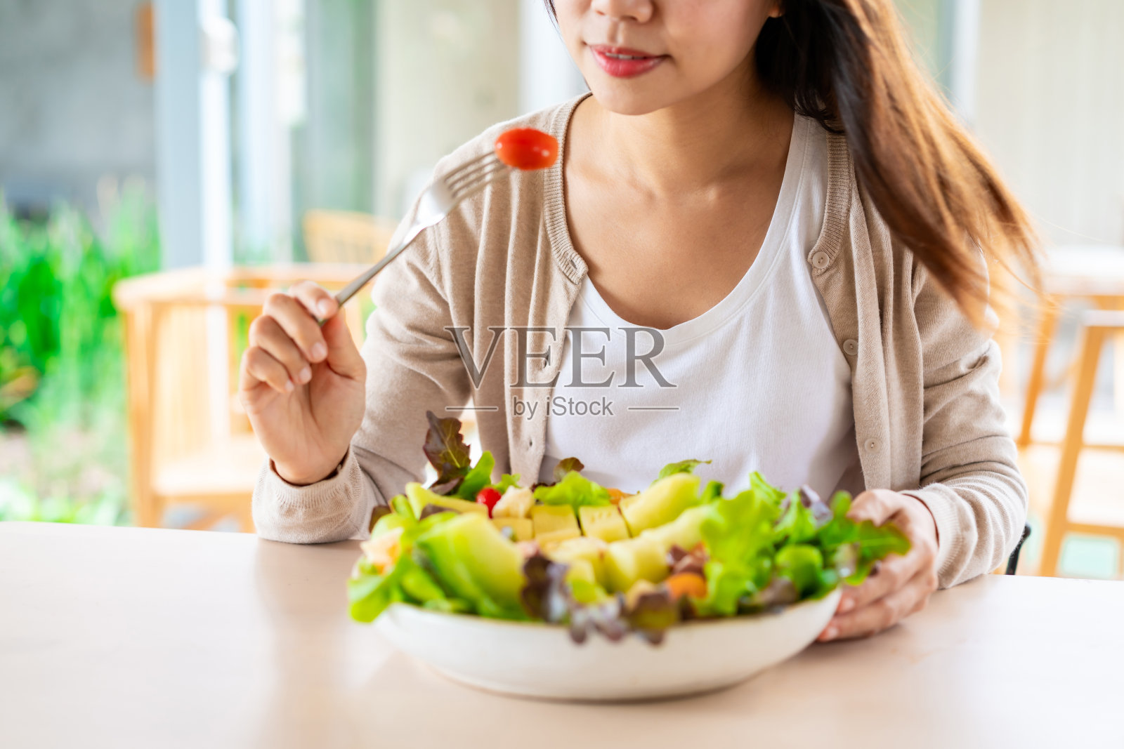年轻女子在餐厅吃健康的蔬菜和水果沙拉，健康的生活方式和饮食理念照片摄影图片