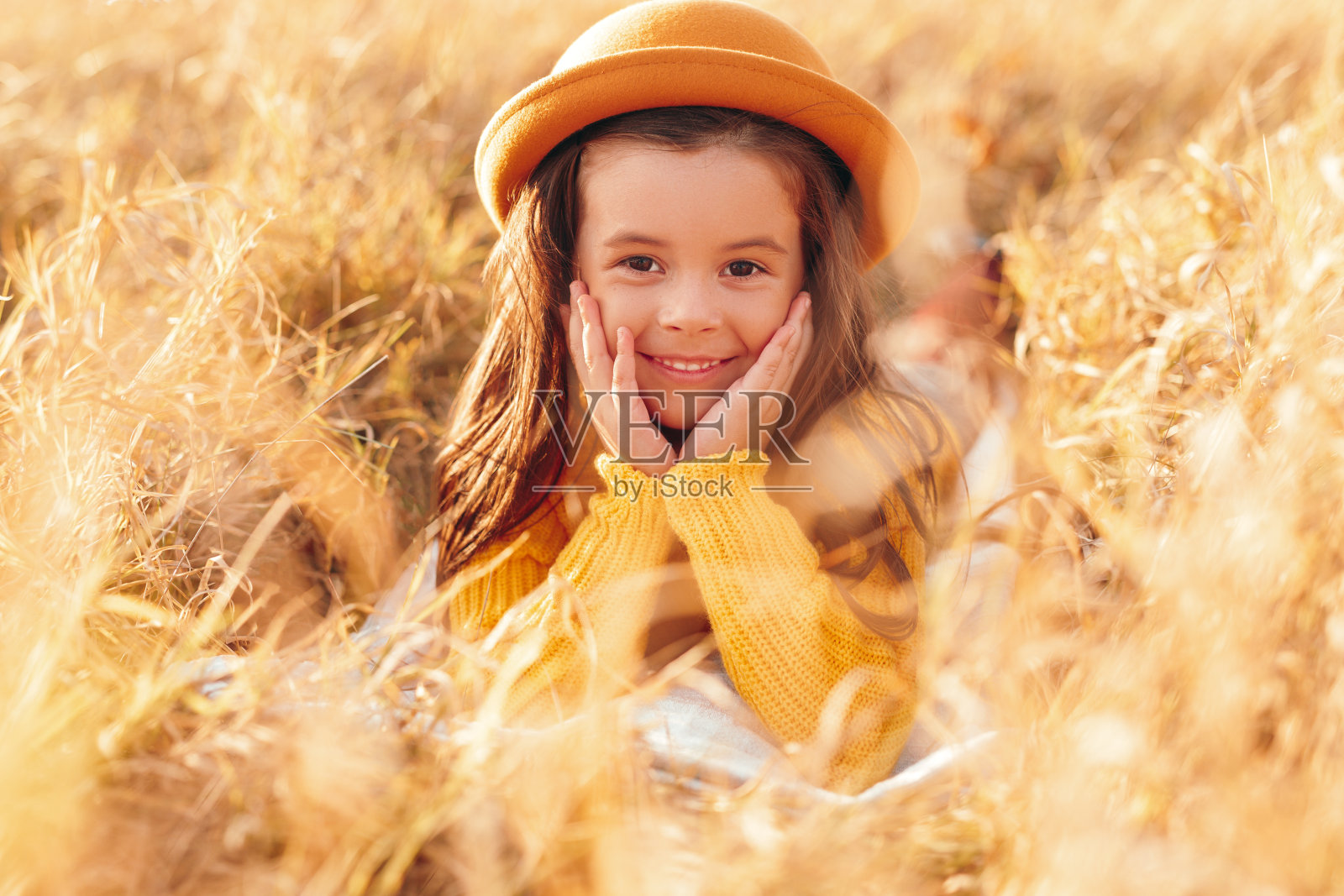 戴着帽子的快乐女孩在黄色的田野里照片摄影图片