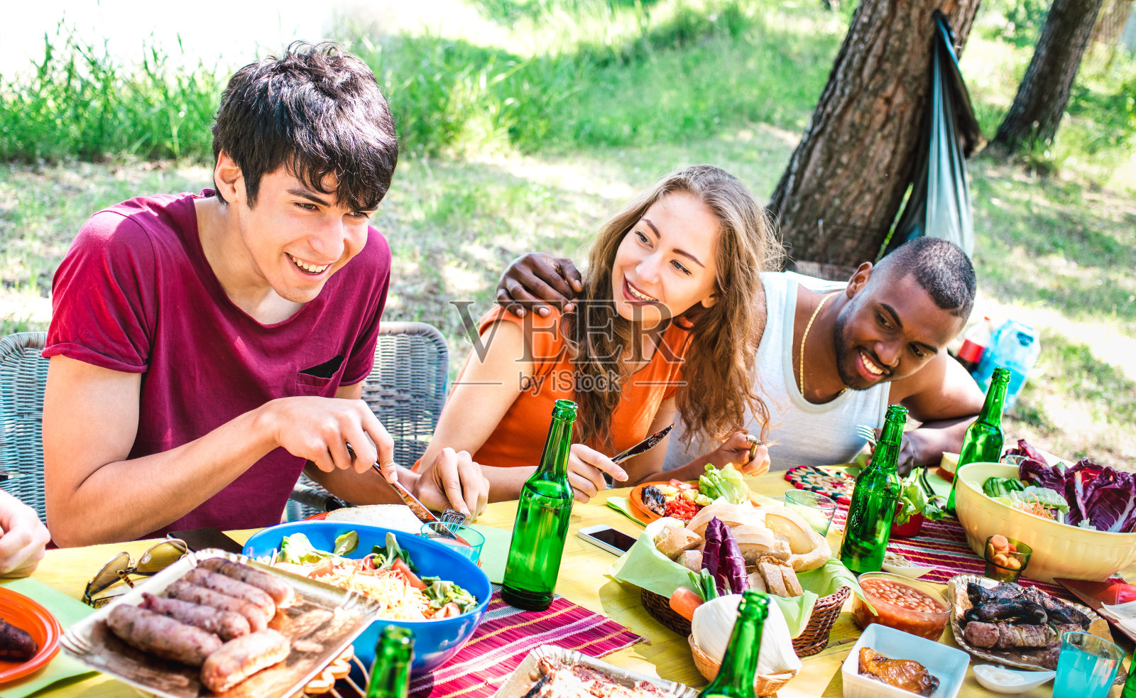 快乐的人一起在烧烤野餐派对-年轻的多种族朋友在picnic社会聚会-青年生活方式概念与男孩和女孩在烧烤-温暖明亮的过滤器照片摄影图片