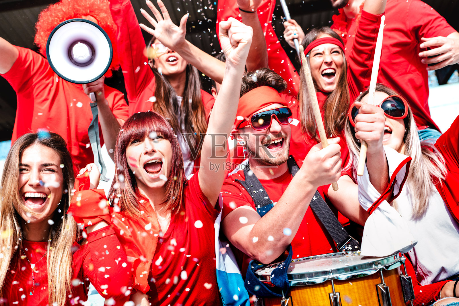 球迷欢呼与五彩纸屑观看足球比赛杯在体育场论坛-年轻人组与红色t恤兴奋的乐趣体育世界锦标赛-明亮生动的滤镜照片摄影图片