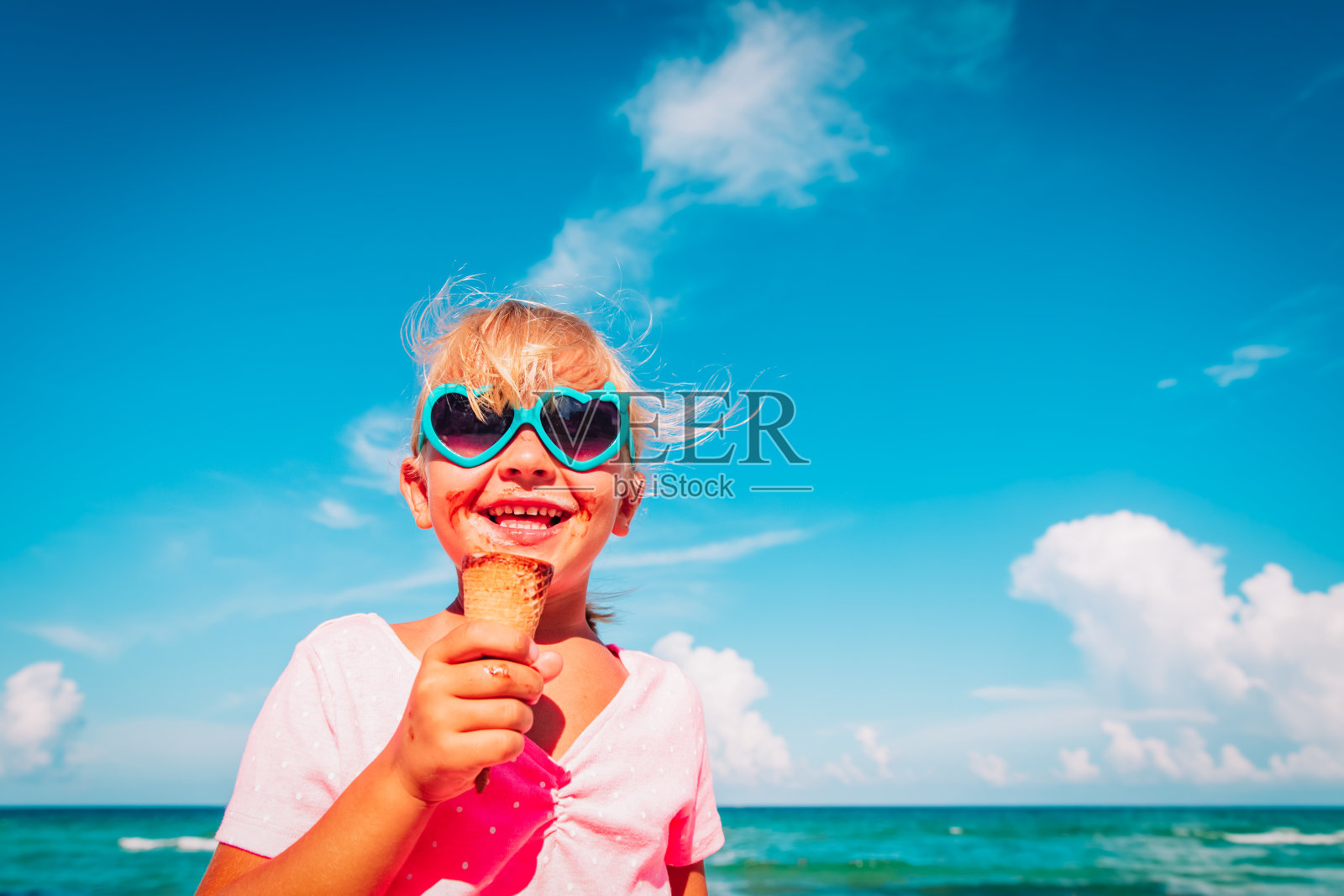 快乐可爱的小女孩在海滩上吃冰淇淋照片摄影图片
