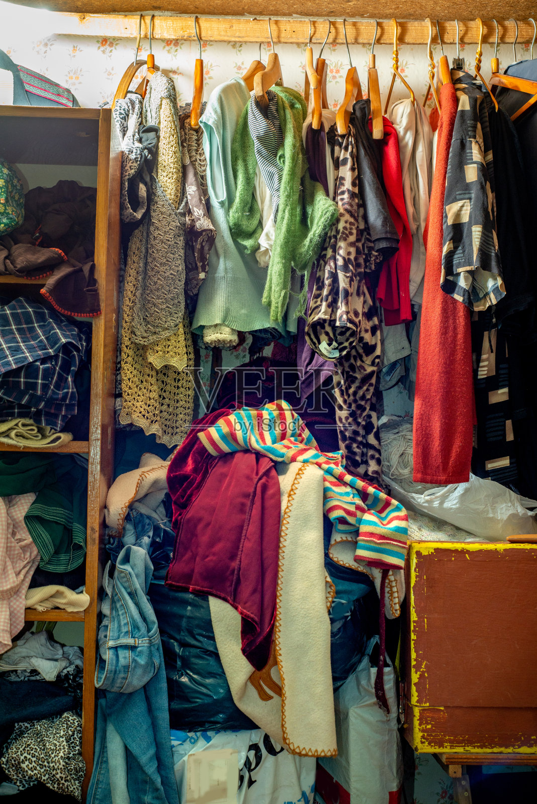 巨大的衣橱里堆满了旧衣服，胡乱地从架子和衣架上往下推挂着。衣柜混乱。衣柜混乱。照片摄影图片