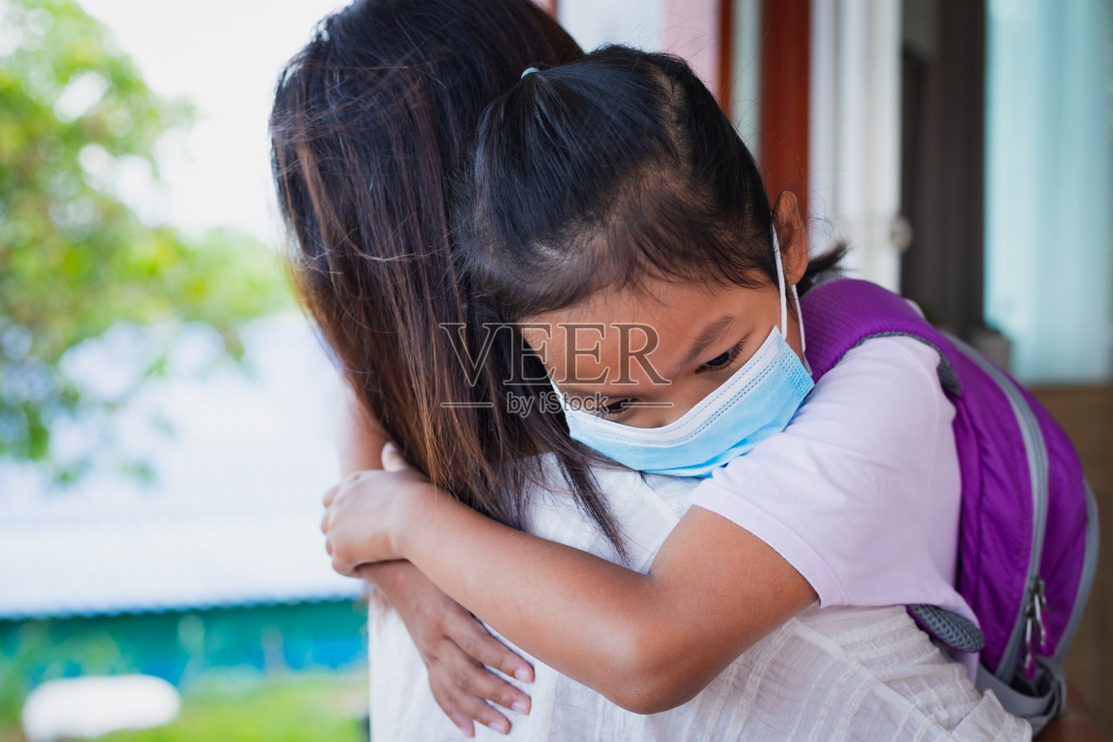 亚洲女童戴医用口罩防护COVID-19病毒爆发前拥抱母亲作为新的正常生活方式。照片摄影图片