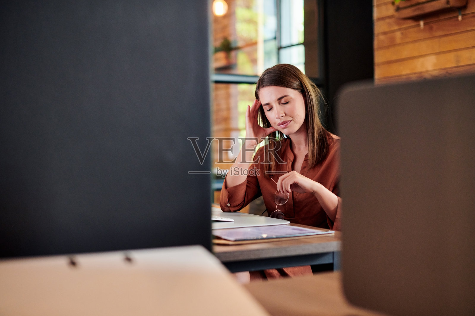 这是一个年轻的女商人在现代办公室里使用电脑的照片，看起来很紧张照片摄影图片