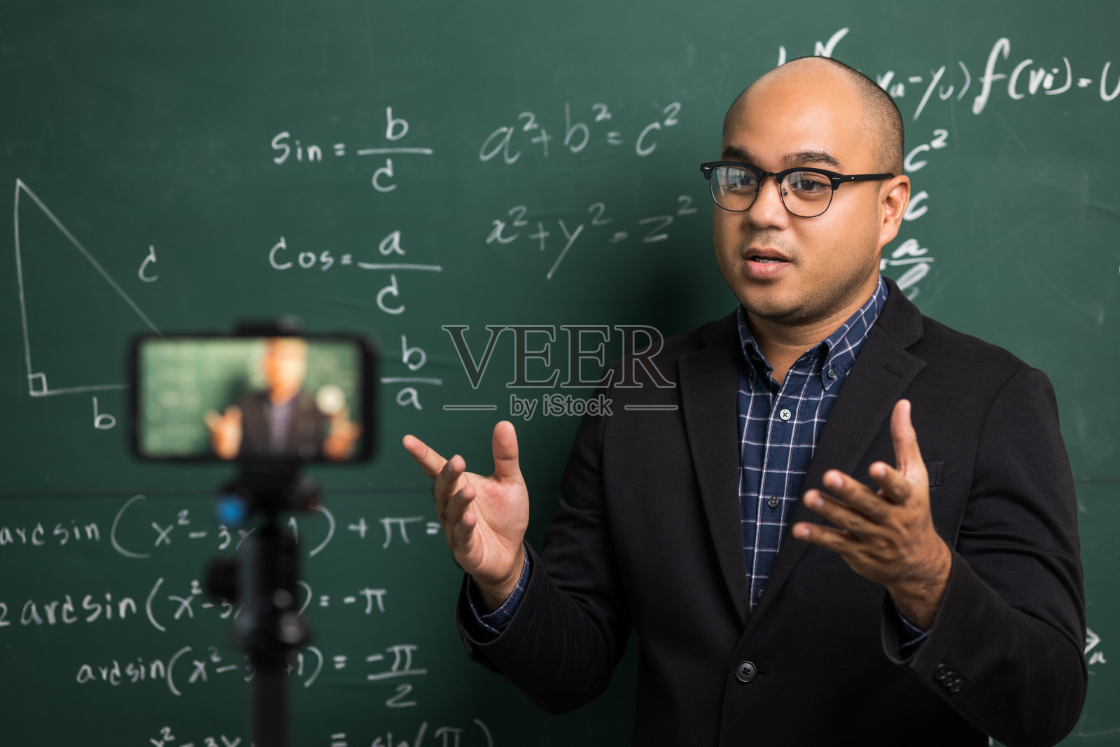 印度年轻教师男子通过智能手机进行在线视频会议直播。亚洲数学教师在线授课，供学生在线学习。照片摄影图片