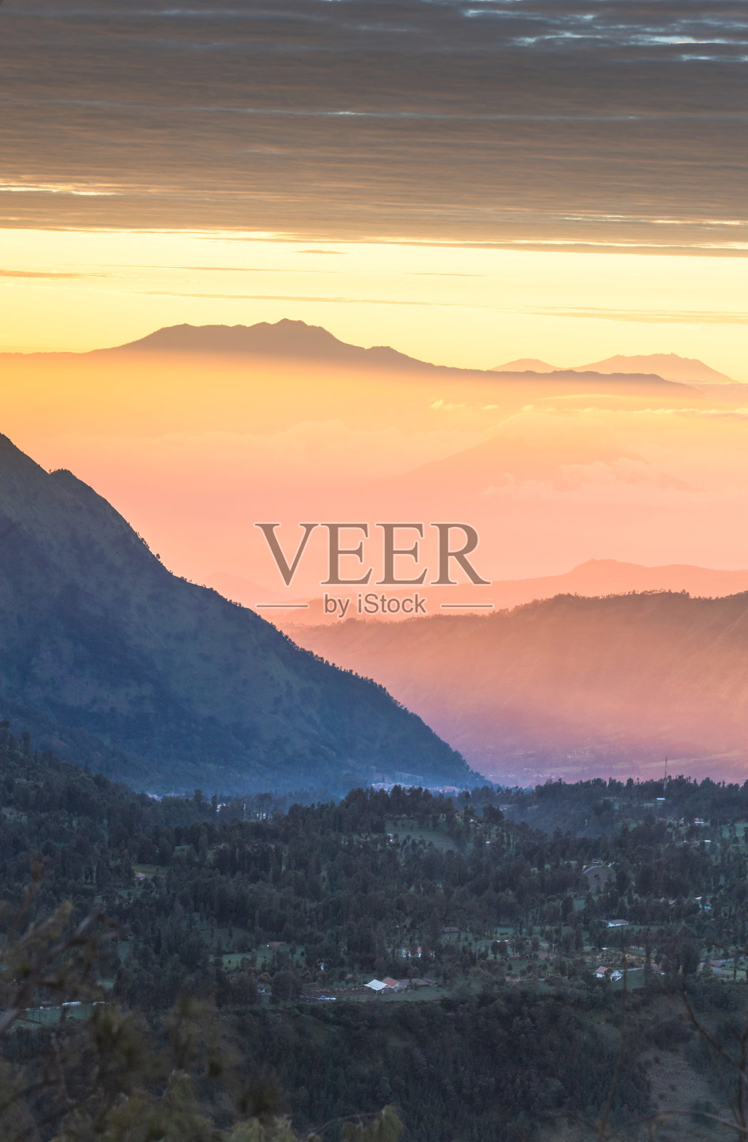 垂直拍摄森林覆盖的雾和薄雾看到大火山背后的布罗莫山在印度尼西亚照片摄影图片