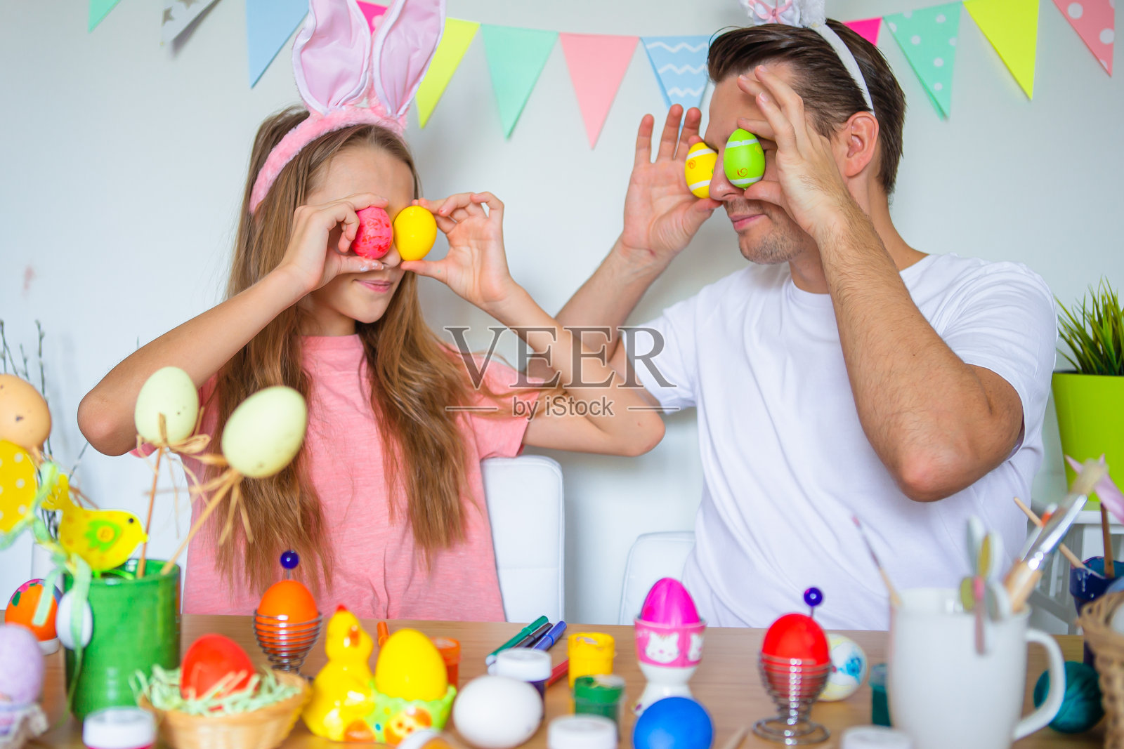 爸爸和他的小女儿在画鸡蛋。快乐的家庭为复活节做准备。照片摄影图片