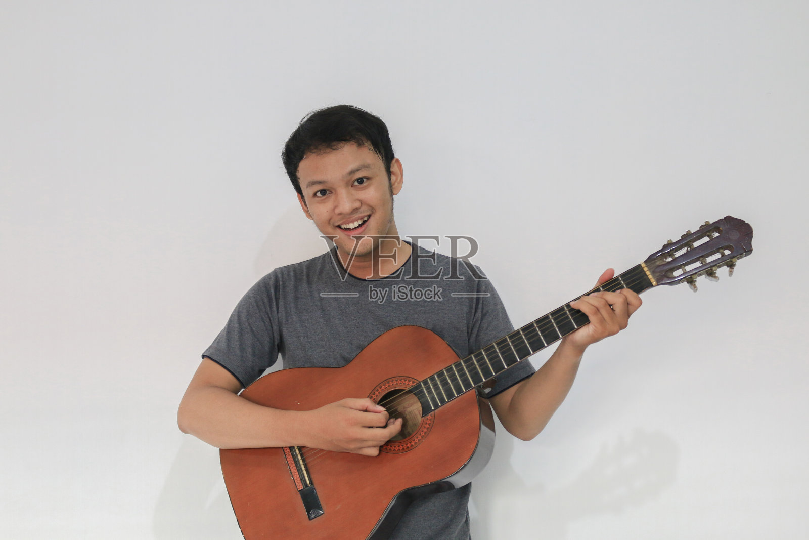 快乐和微笑年轻的亚洲男子音乐家与吉他照片摄影图片