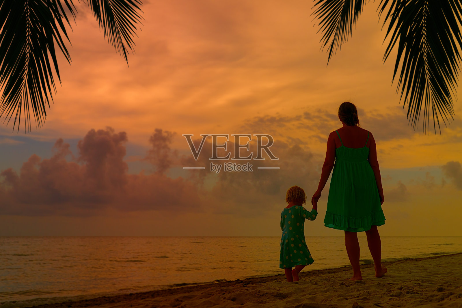 日落时分，母亲和小女儿在海滩上散步照片摄影图片