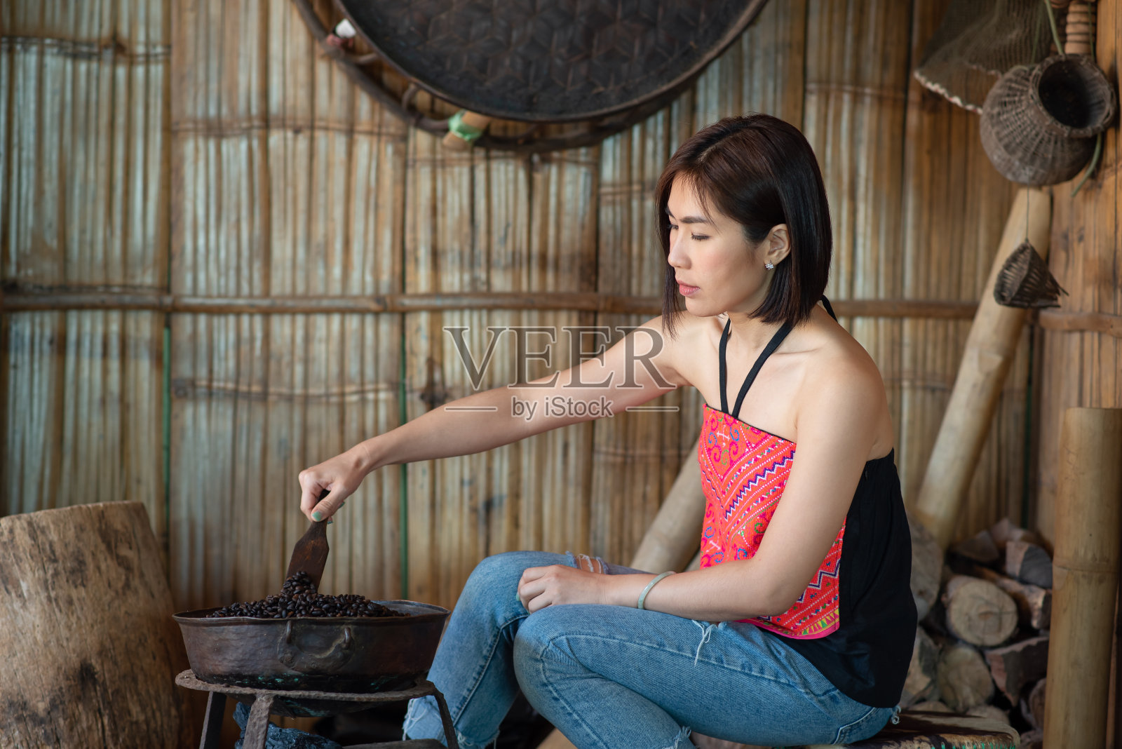 在泰国清莱省班法希的一个咖啡种植园里，年轻的亚洲女性旅行者用传统的方法烘焙咖啡豆照片摄影图片