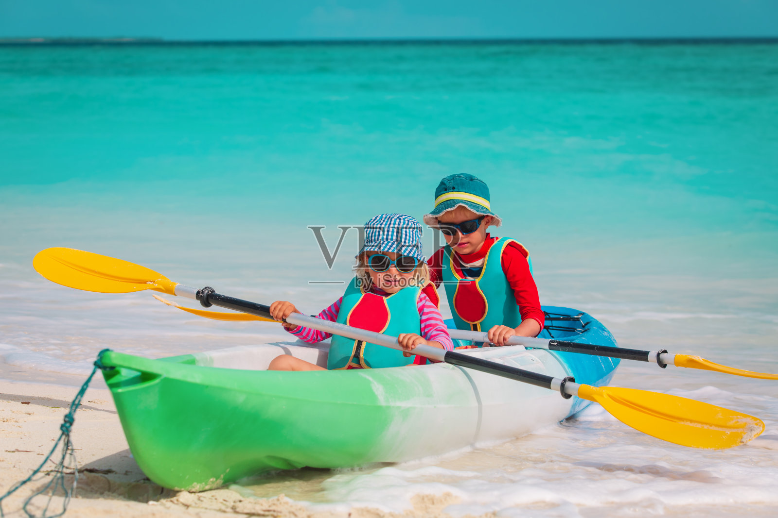 可爱的小男孩和小女孩在海滩上划皮艇照片摄影图片