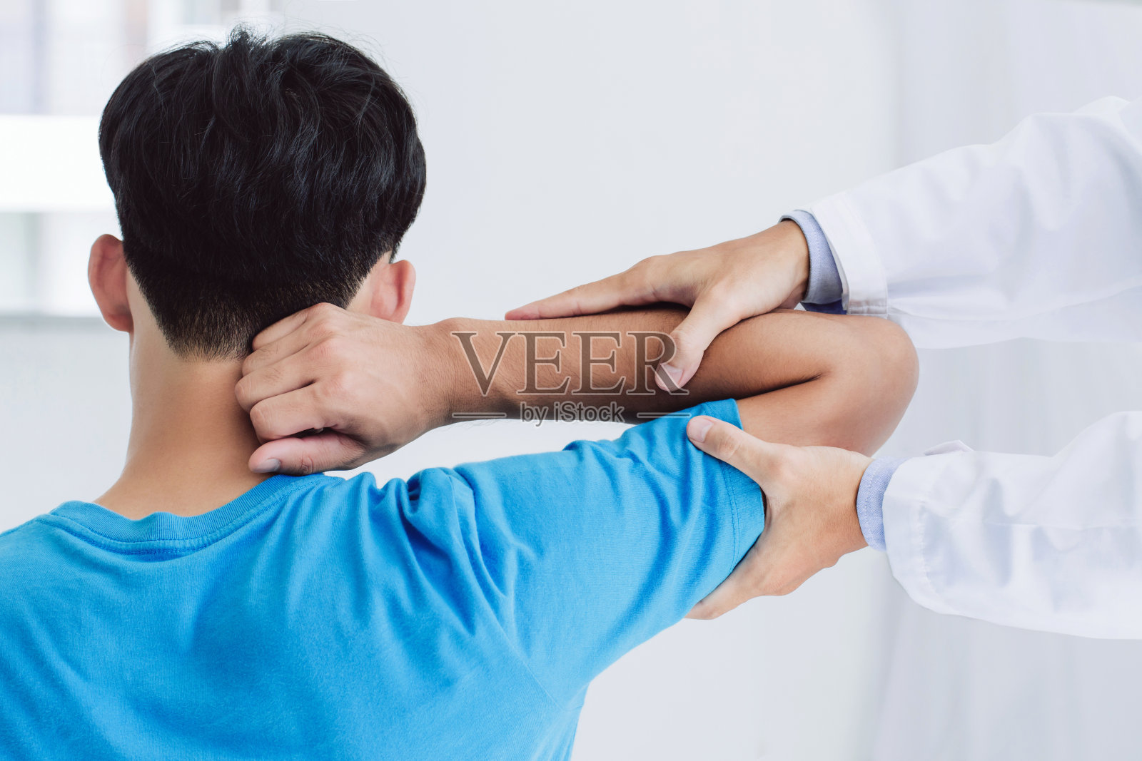 专业物理治疗师协助男性病人在诊所检查手臂受伤的病人。在门诊进行疼痛康复治疗。康复理疗的概念。照片摄影图片