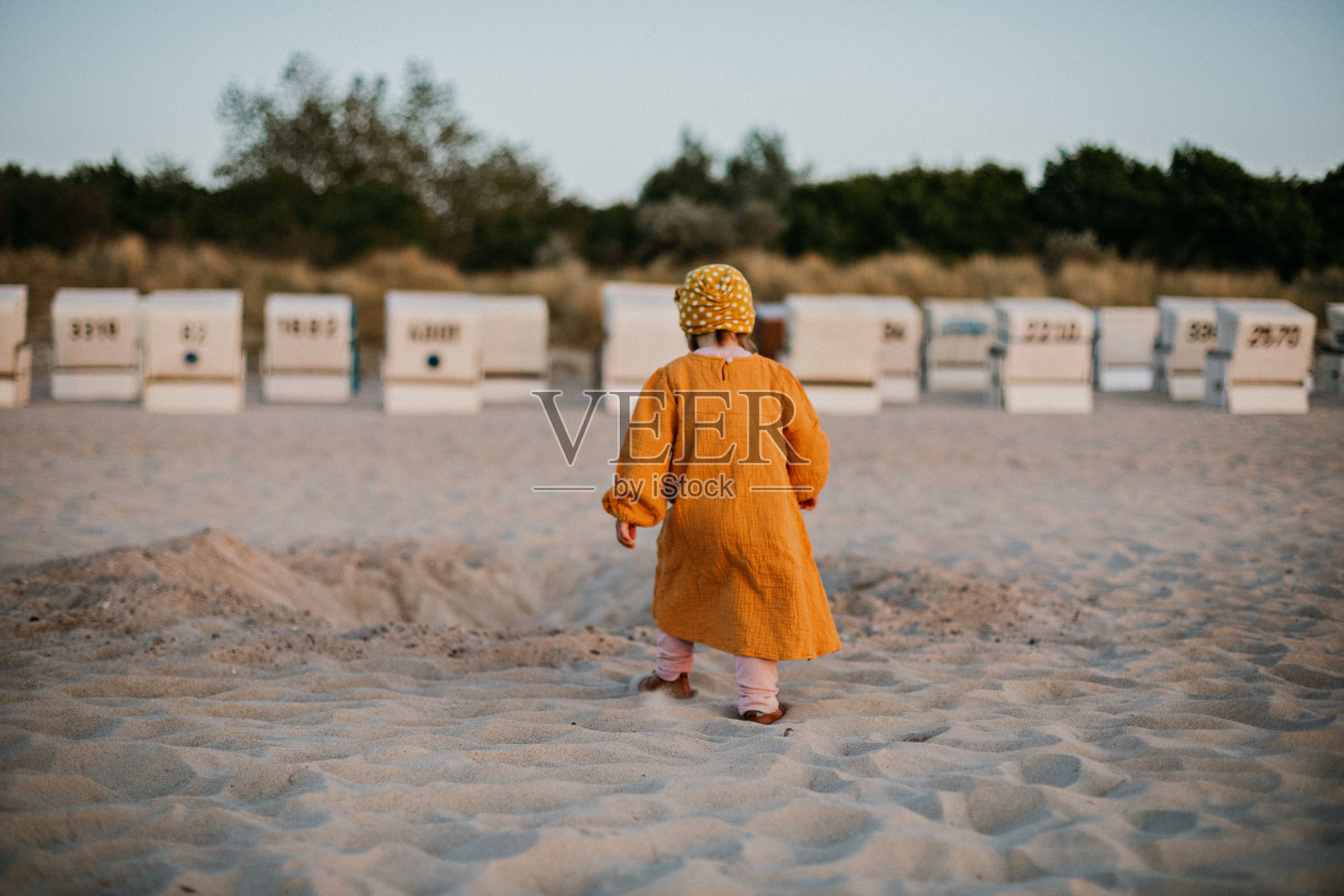 一个孩子走在波罗的海的日落海滩上，篮子中间照片摄影图片