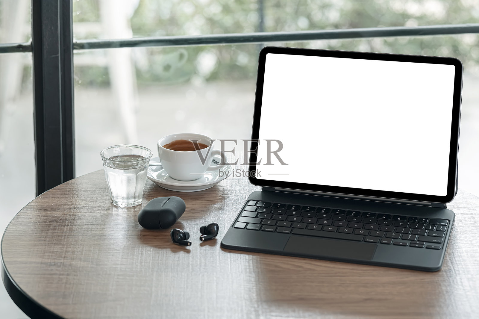 黑屏平板电脑键盘和一杯咖啡在咖啡馆的圆桌木桌上。照片摄影图片