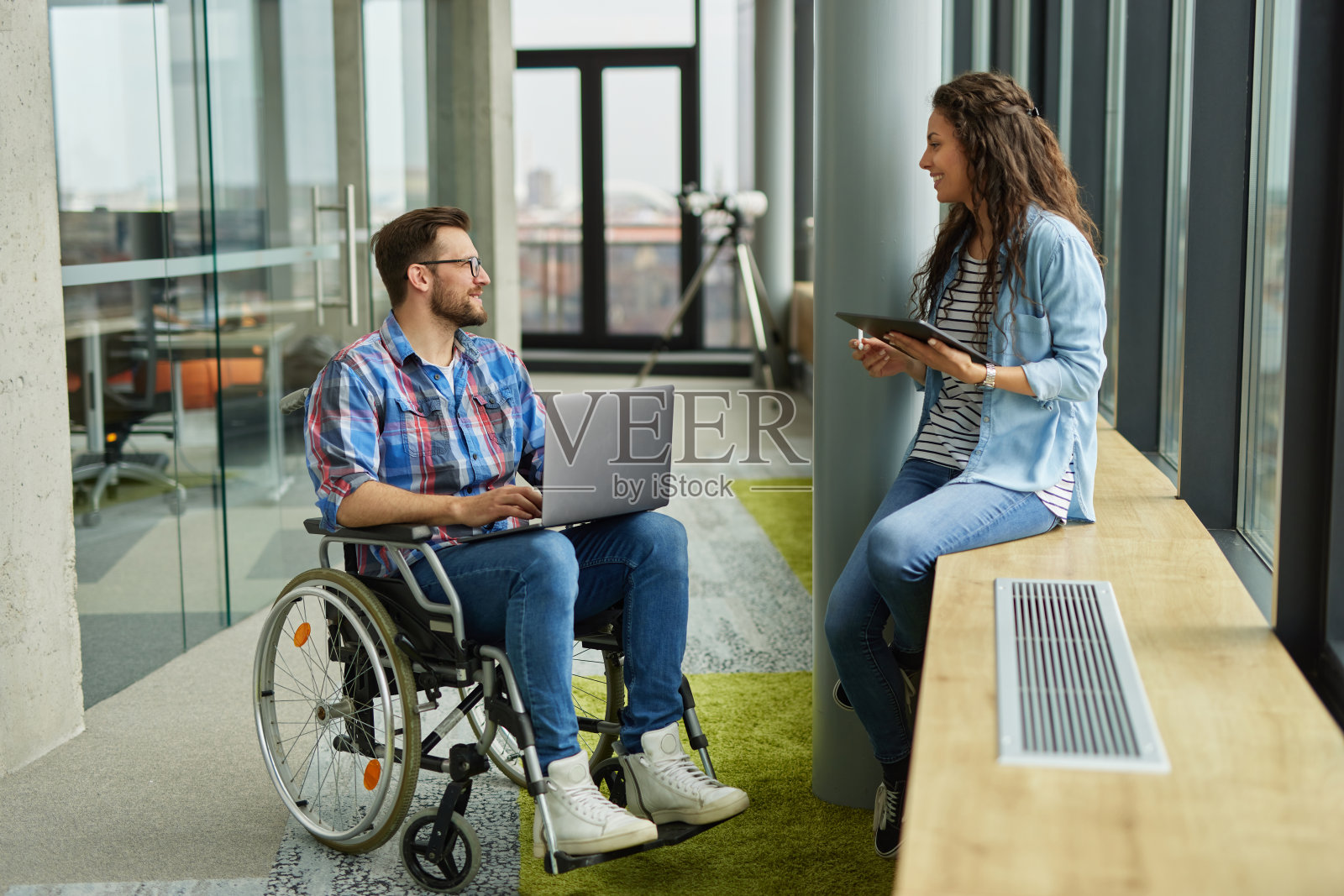 瘫痪的男电脑程序员在办公室走廊与女同事讨论照片摄影图片