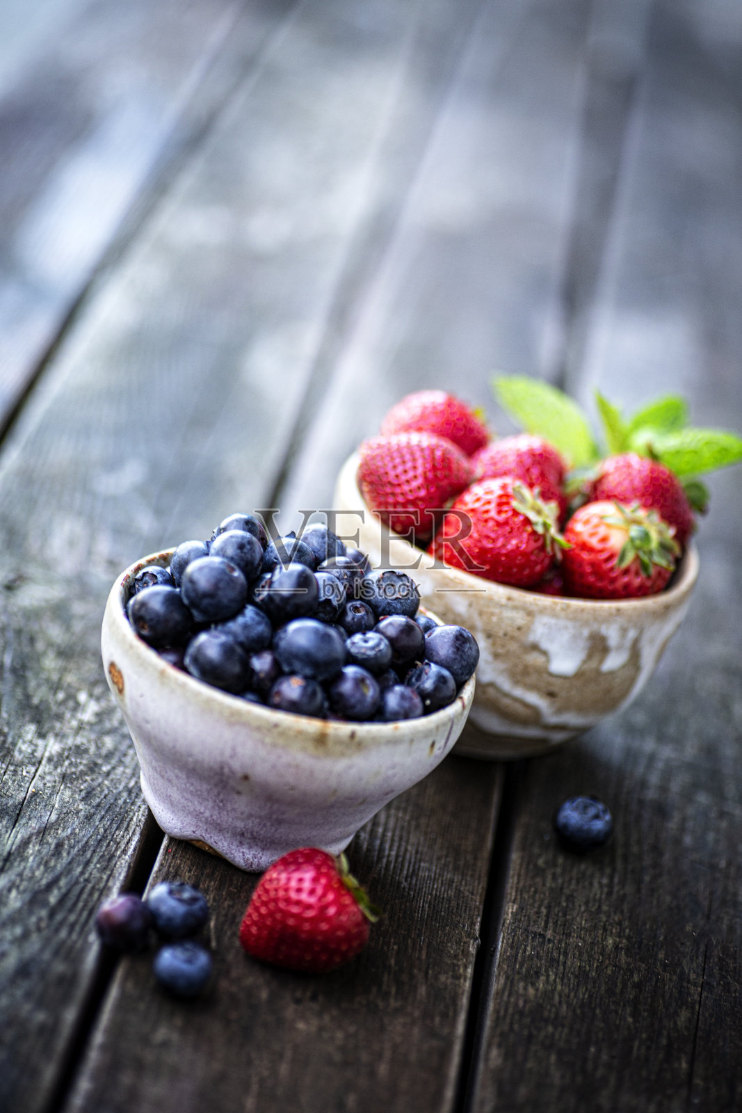 木背景上的陶瓷碗里的蓝莓和草莓照片摄影图片