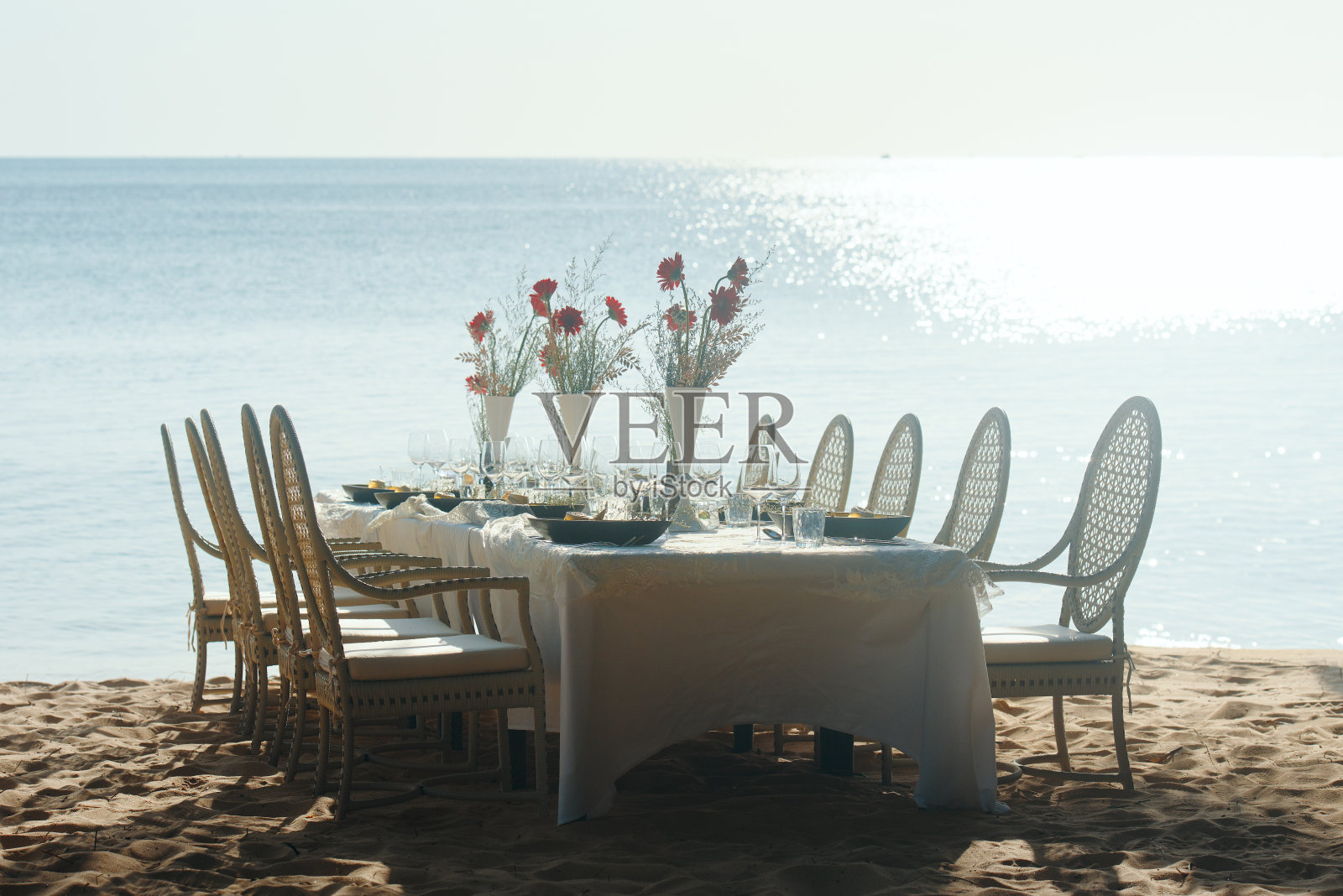 阳光明媚的海滩上的节日餐桌。照片摄影图片