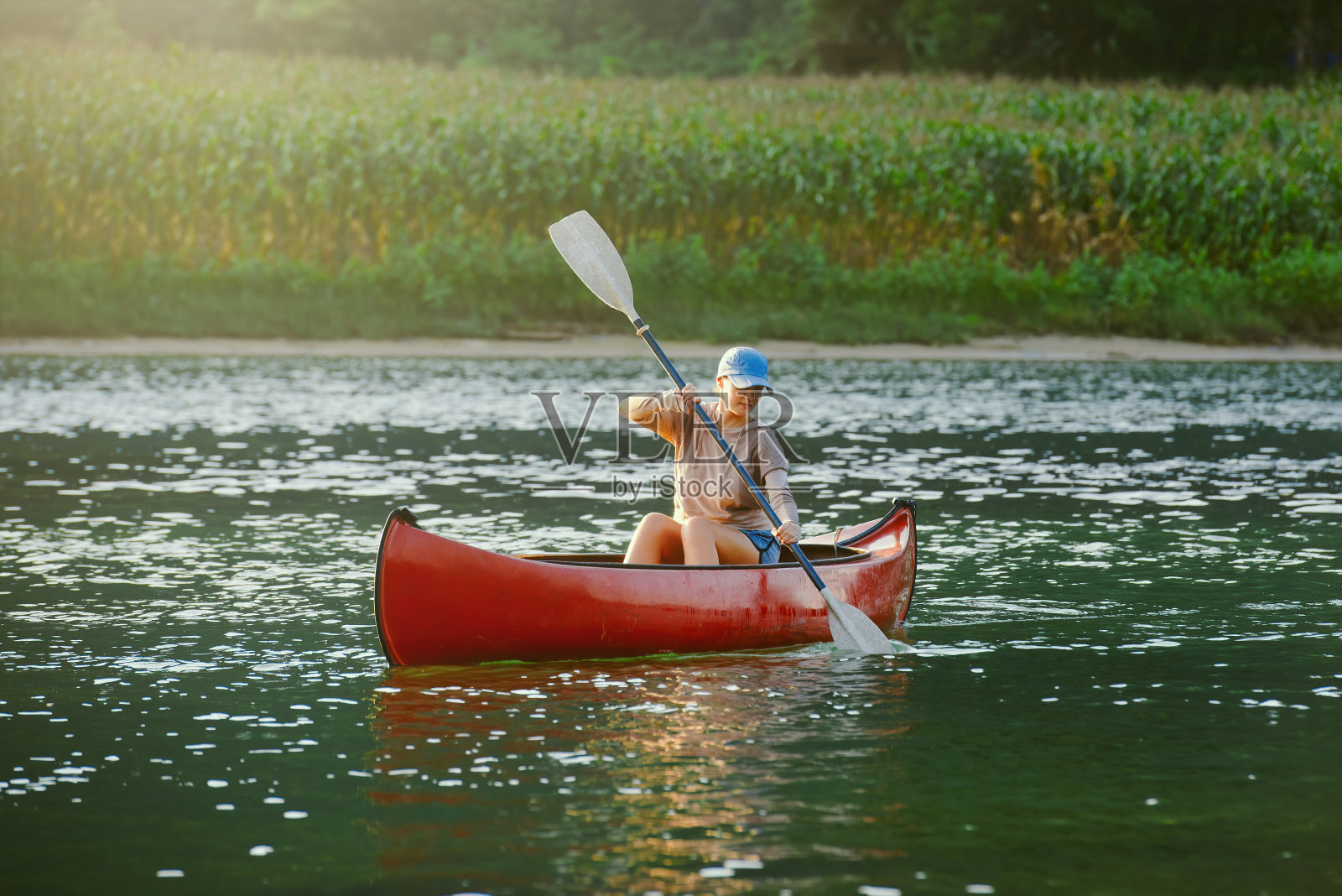 在乡村的河流上，妇女在皮划艇上游泳。照片摄影图片