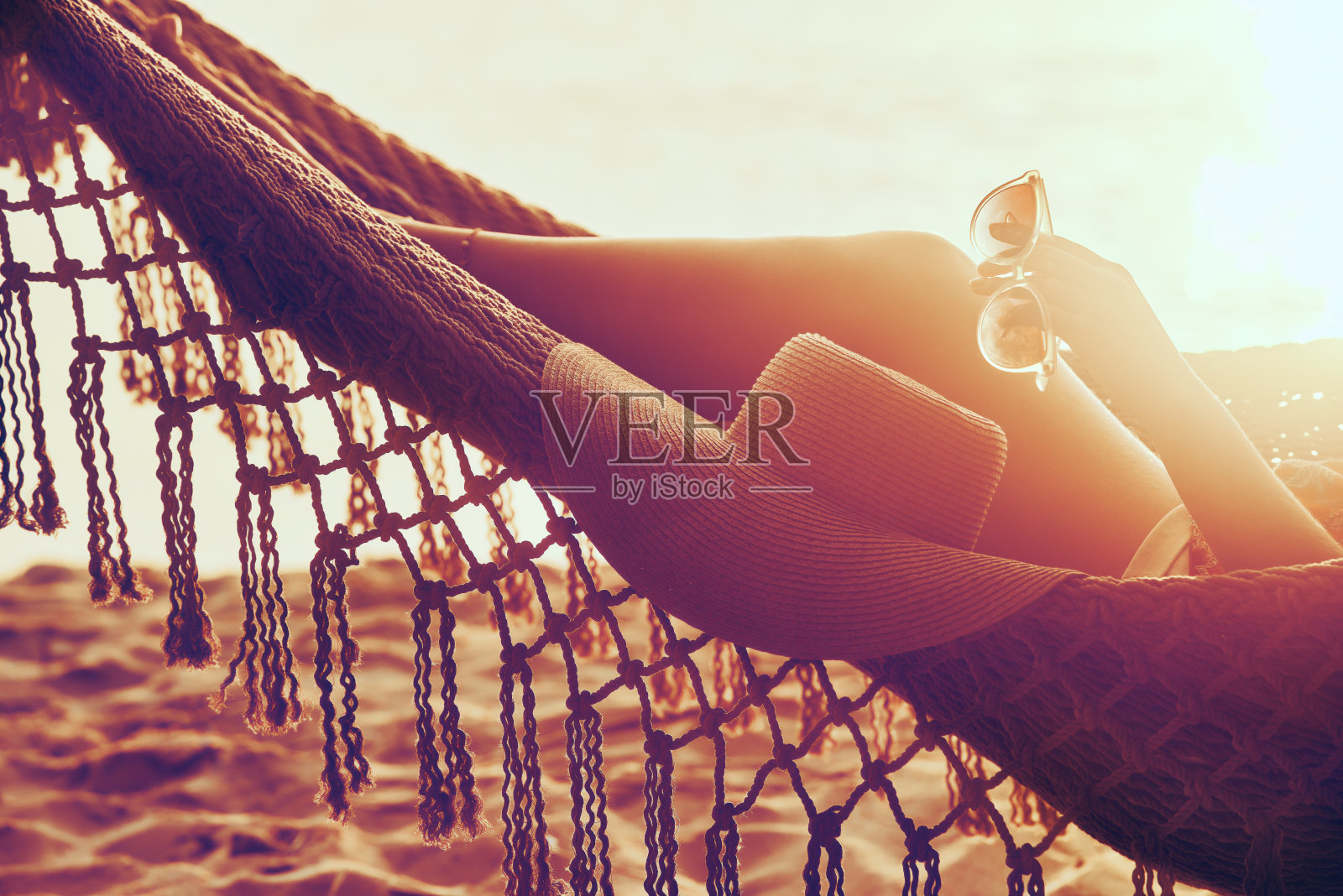 沙滩上吊床上年轻女子的脚。度假海滩夏季度假概念。照片摄影图片