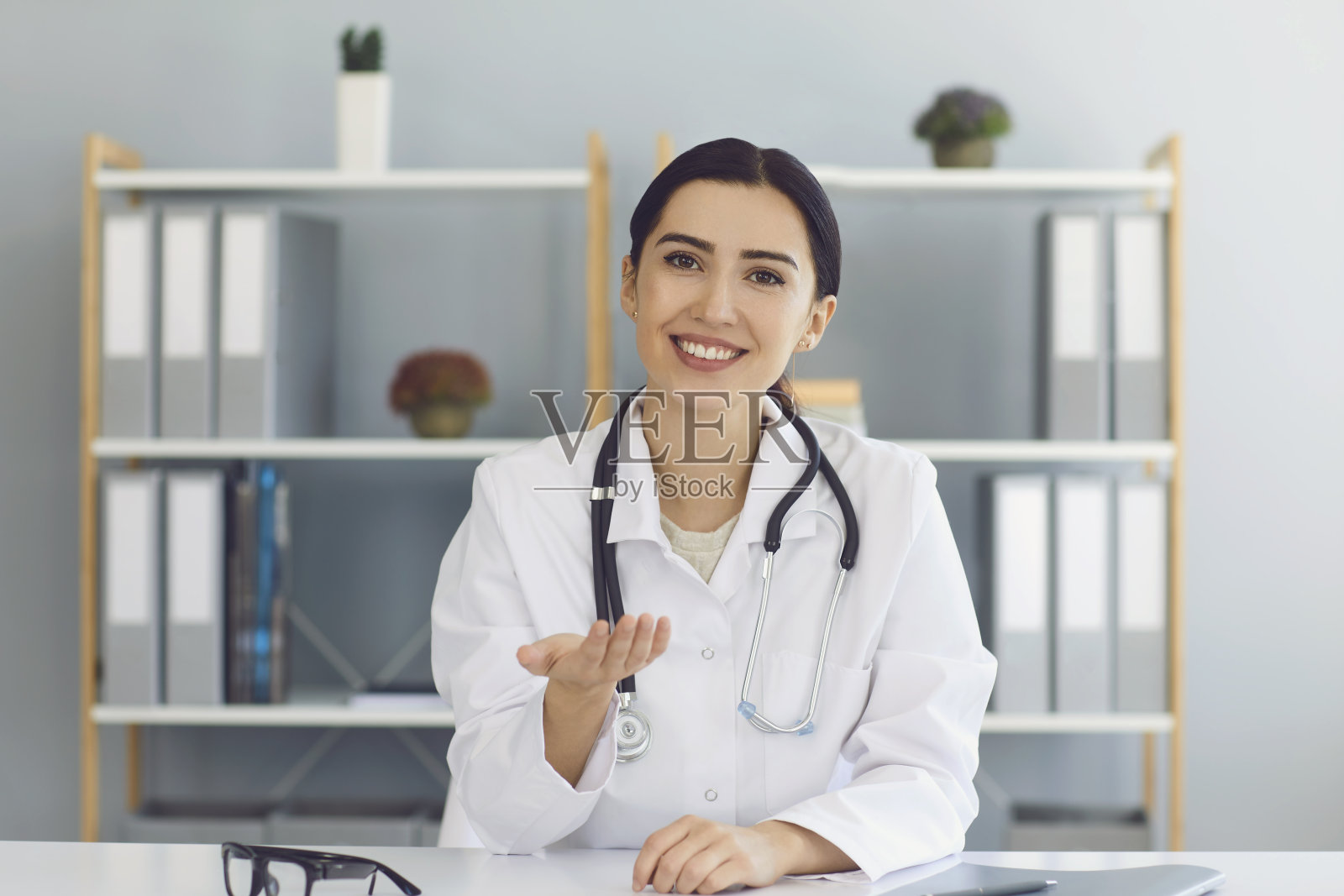 微笑的女医生在诊所在线为患者提供医疗咨询。年轻的全科医生通过网络与客户沟通照片摄影图片