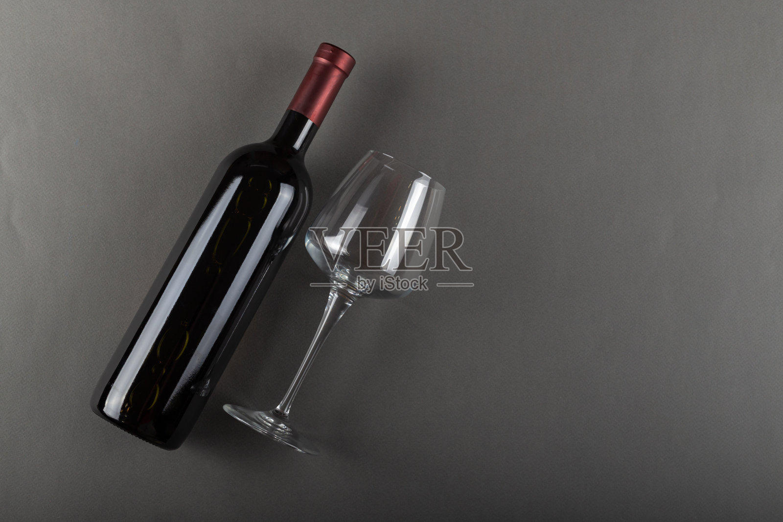 灰色背景上的红酒瓶和空酒杯。酒精饮料。酿酒的概念。空间的文本。照片摄影图片