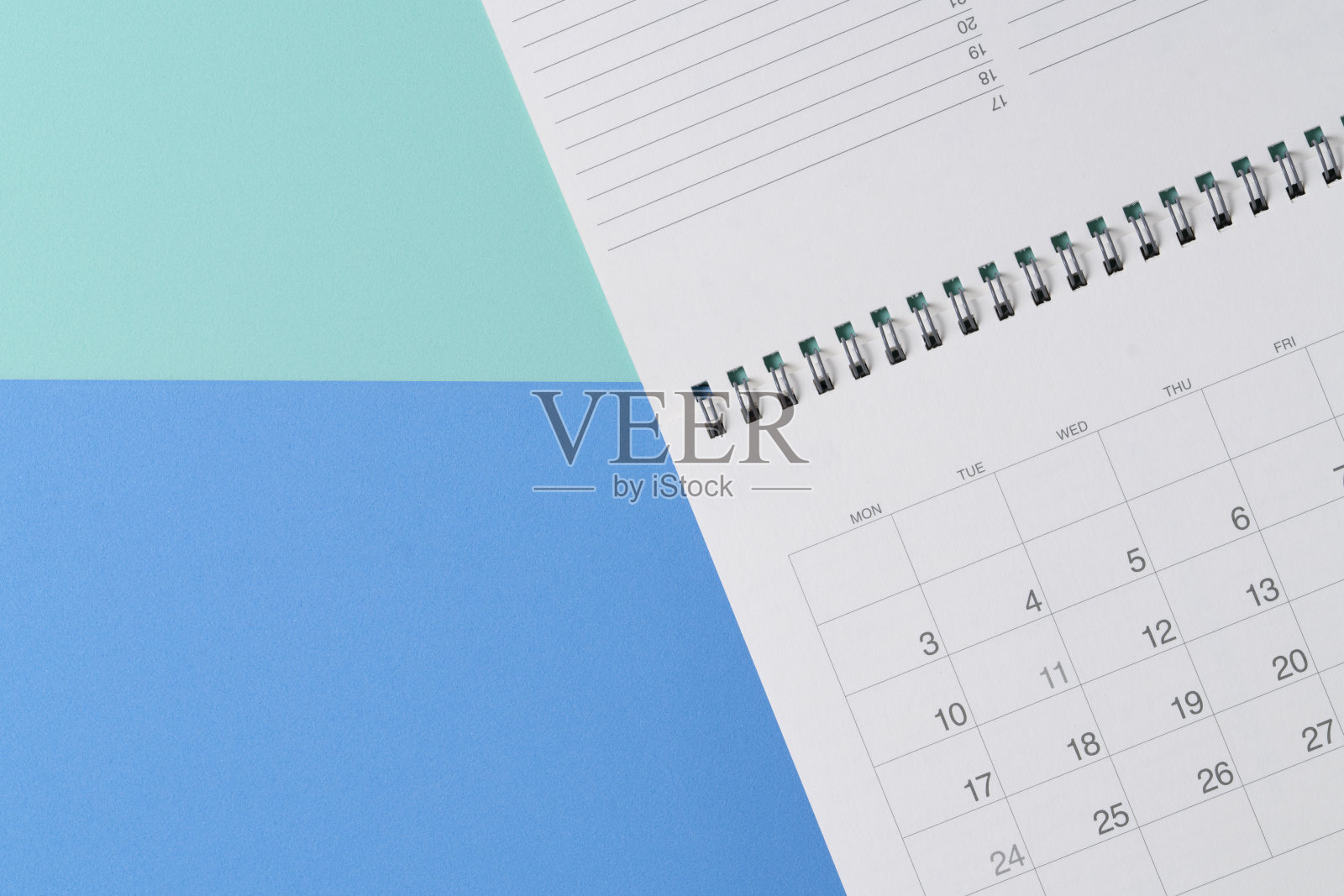 近距离的日历放在蓝色和绿色的桌子背景上，规划商务会议或旅行计划的概念照片摄影图片