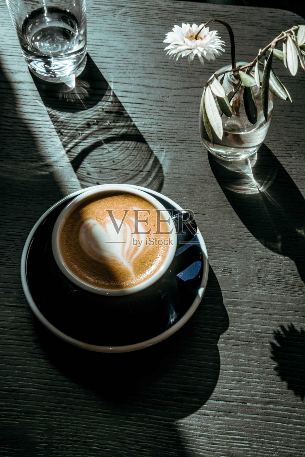 卡布奇诺咖啡杯放在黑色木制桌子上的灯光和阴影照片摄影图片