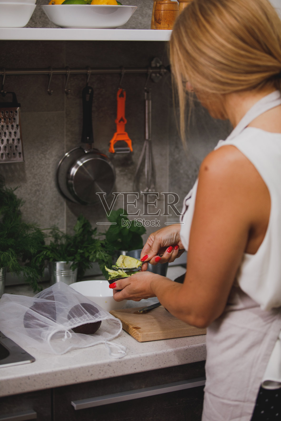 女人在准备午餐的时候用勺子舀鳄梨照片摄影图片