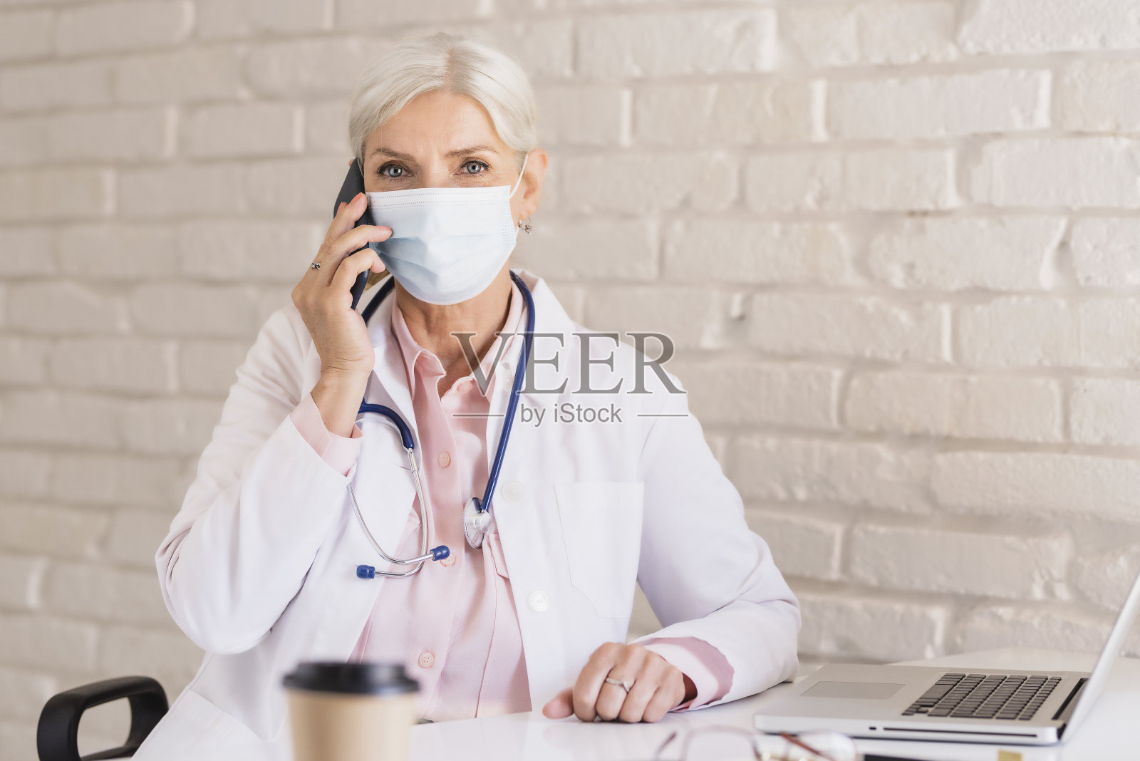 女医生的肖像，戴着口罩，在医生办公室工作照片摄影图片