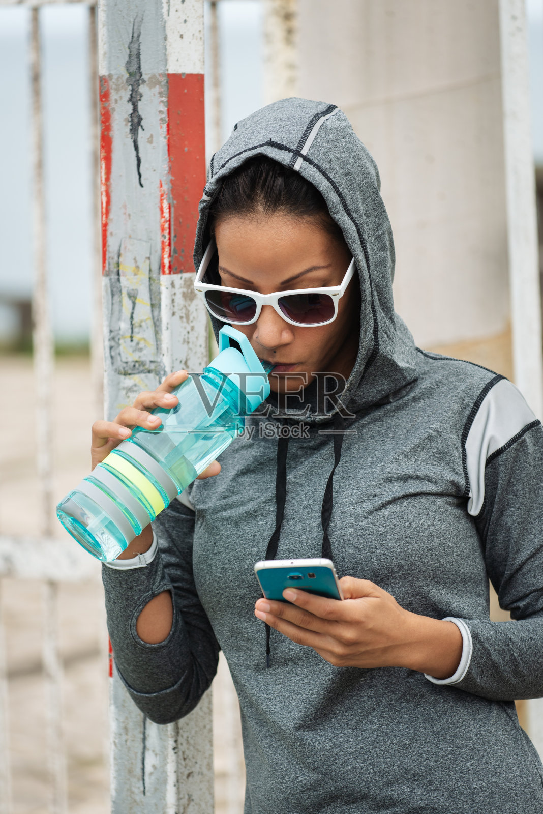 城市健身女性喝水和使用智能手机照片摄影图片