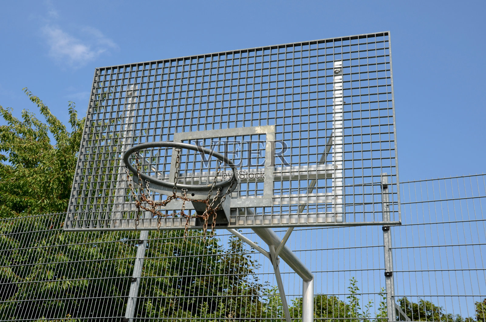 学校的多功能户外球类运动场地。绿色人造草皮从塑料地毯与线条。篮球圈和足球球门。在高高的网和护栏周围照片摄影图片