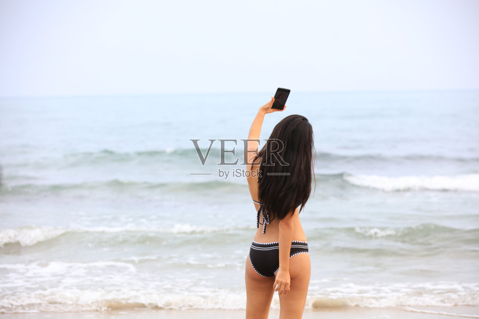 性感女子身穿黑色比基尼站在自拍照片用手机拍摄照片摄影图片