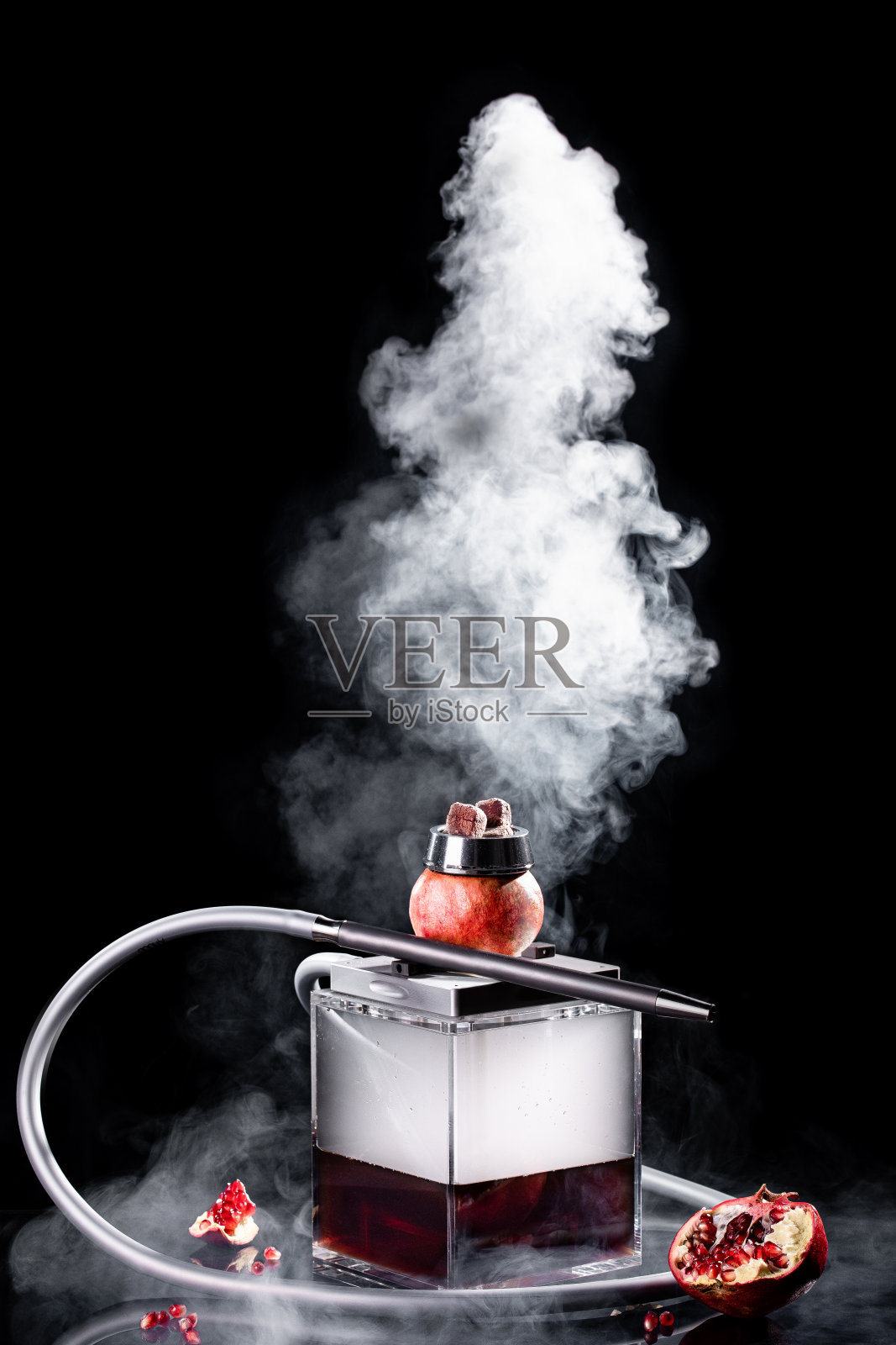 水烟水烟与玻璃烧瓶和水果石榴碗白色烟在黑色的背景。传统的东方放松照片摄影图片