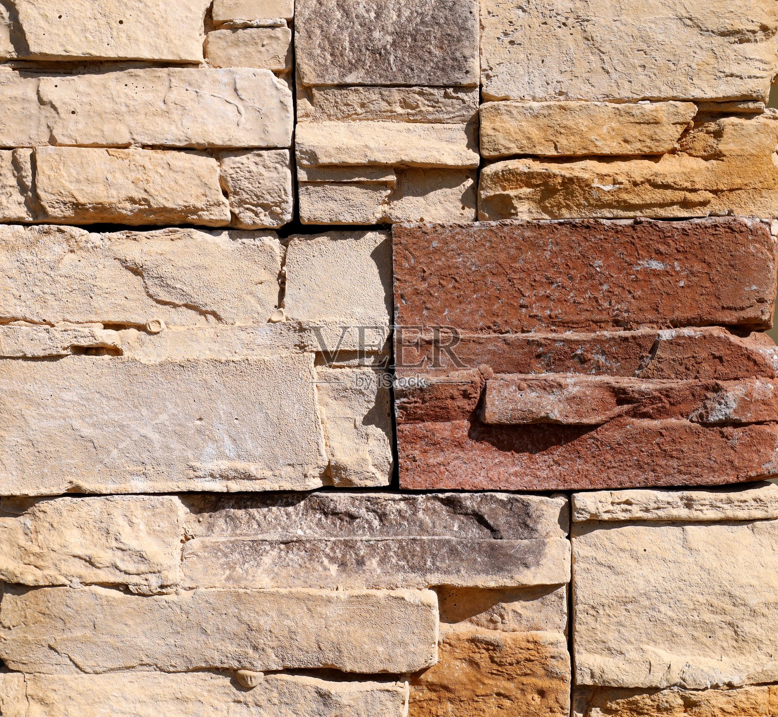 米色和棕色外墙覆层由不规则的石头砖制成。照片摄影图片