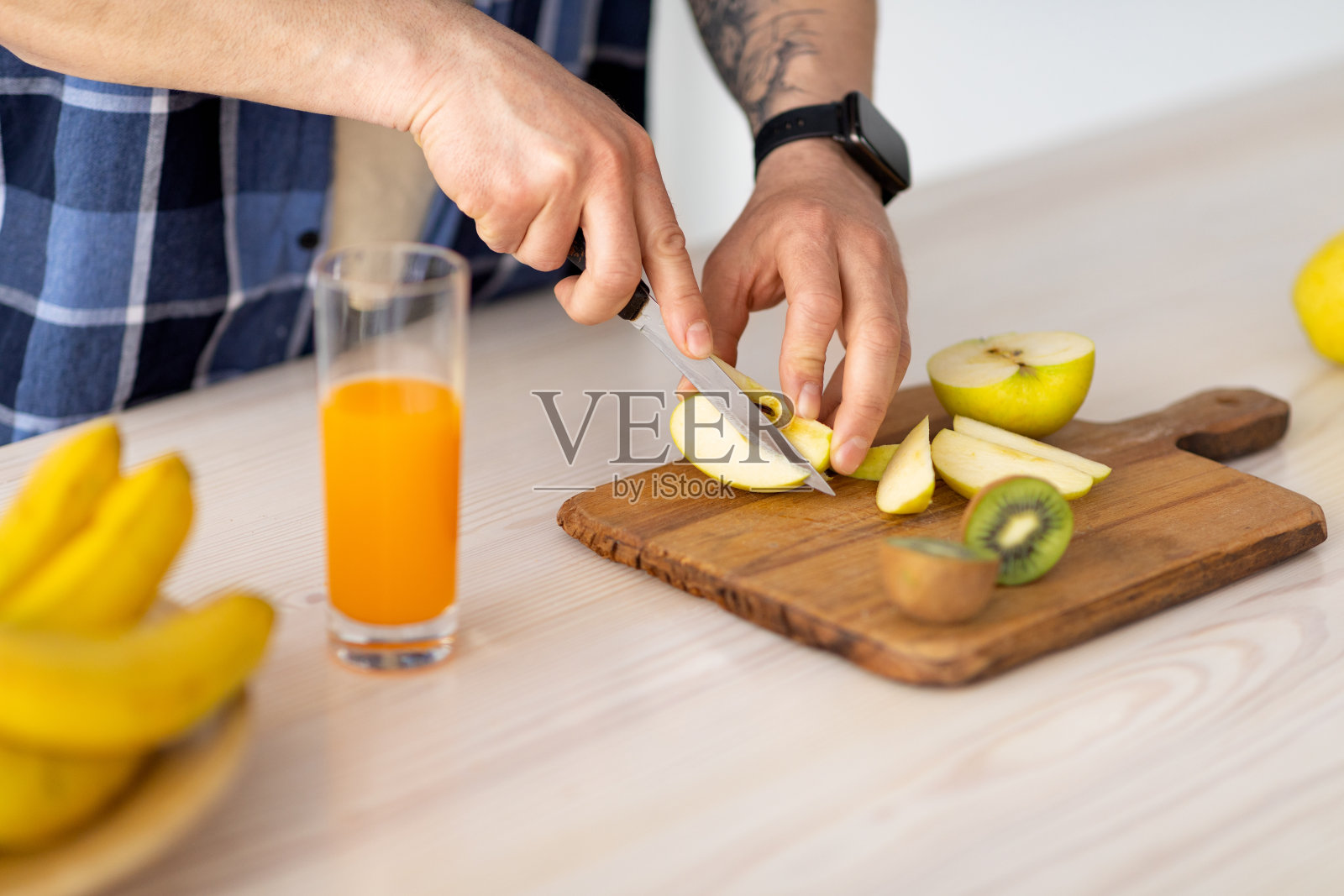 一个面目全非的成熟男人，把水果切成奶昔或鲜榨果汁，在厨房的桌子上准备饭菜照片摄影图片