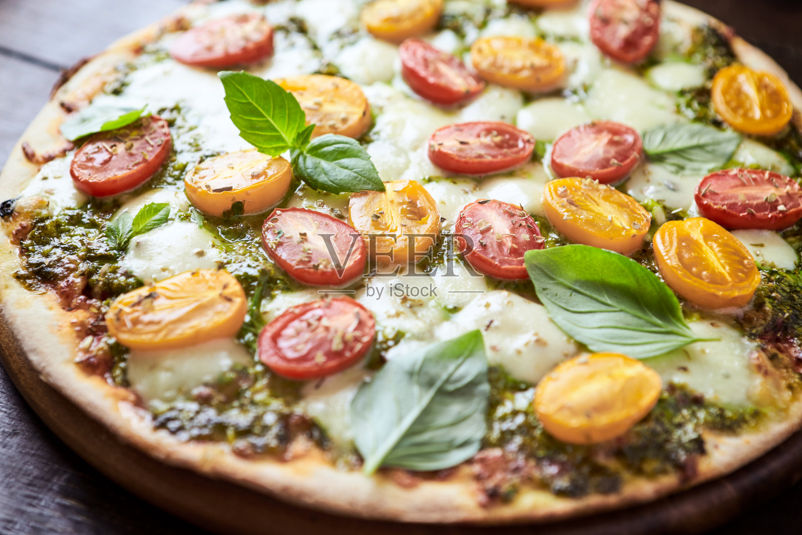 圣女果，马苏里拉奶酪和罗勒香蒜酱的披萨。深色木制背景。关闭了。照片摄影图片
