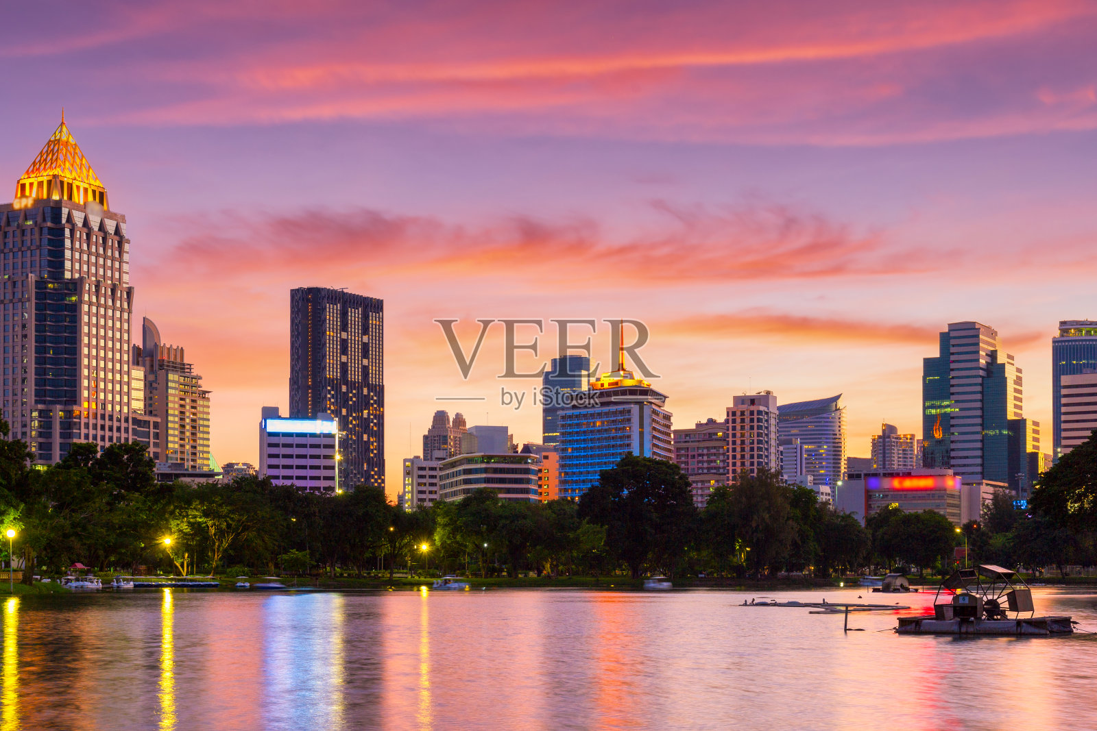 泰国曼谷，市中心公园的自然湖，有商业建筑和日落天空的背景照片摄影图片