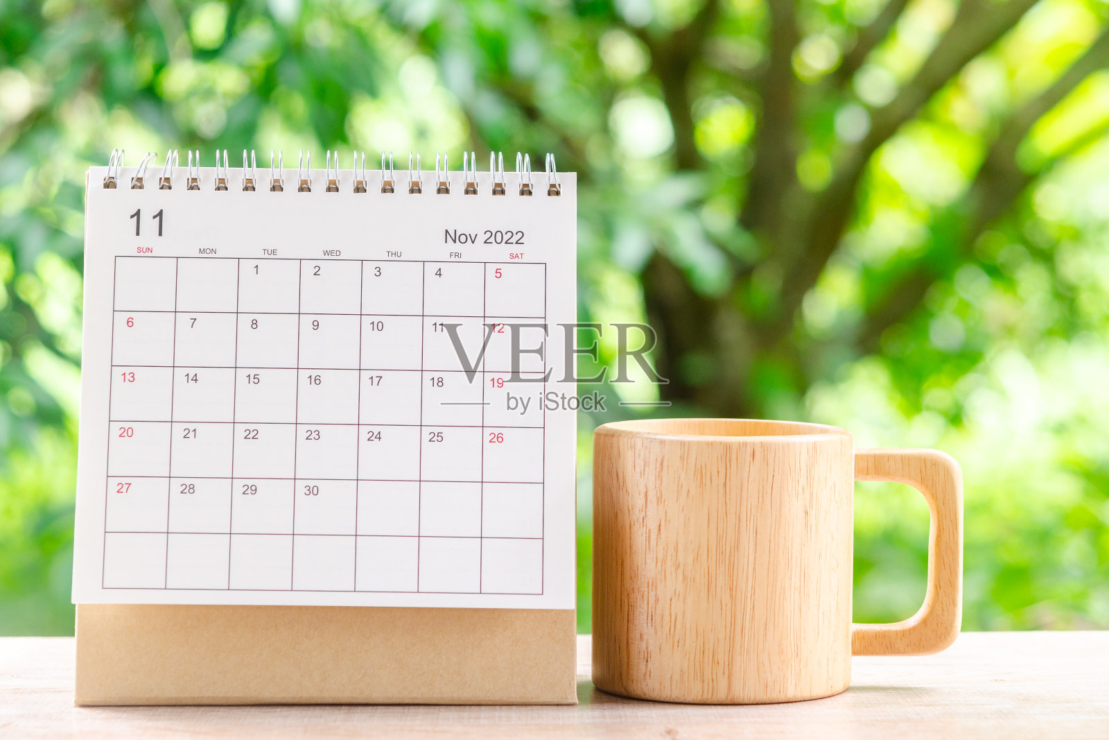 11月，2022年日历桌，供主办方在木桌上规划和提醒，以绿色自然为背景。照片摄影图片
