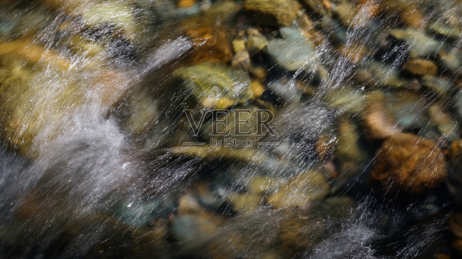 岩石山底河流穿过清澈的河水，选择性聚焦，画面模糊。溪水中的水晶水在阳光下闪闪发光。石头的背景照片摄影图片